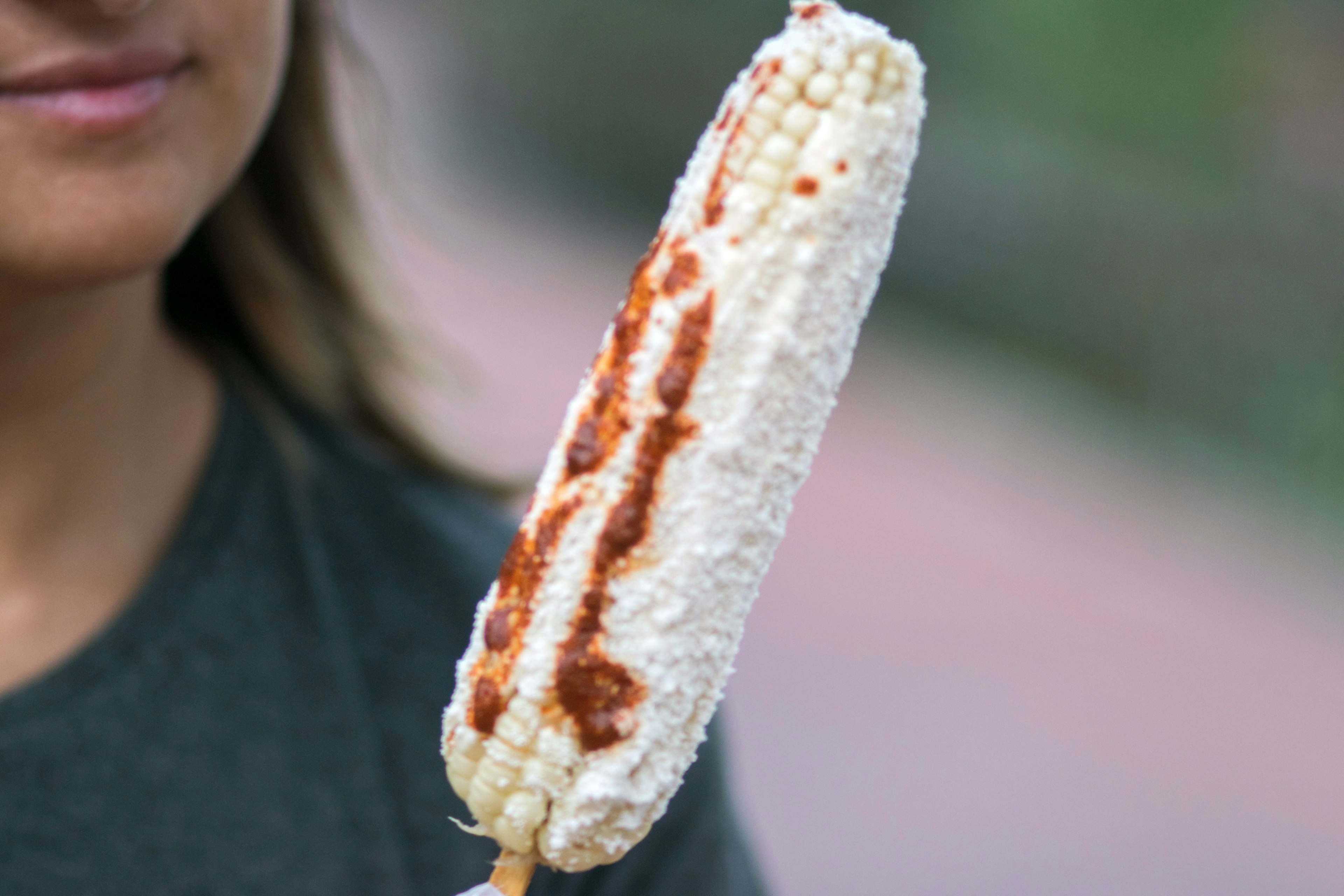 Portrait Of Young Woman Eating Corn with hot sauce in Valladolid, Mexico