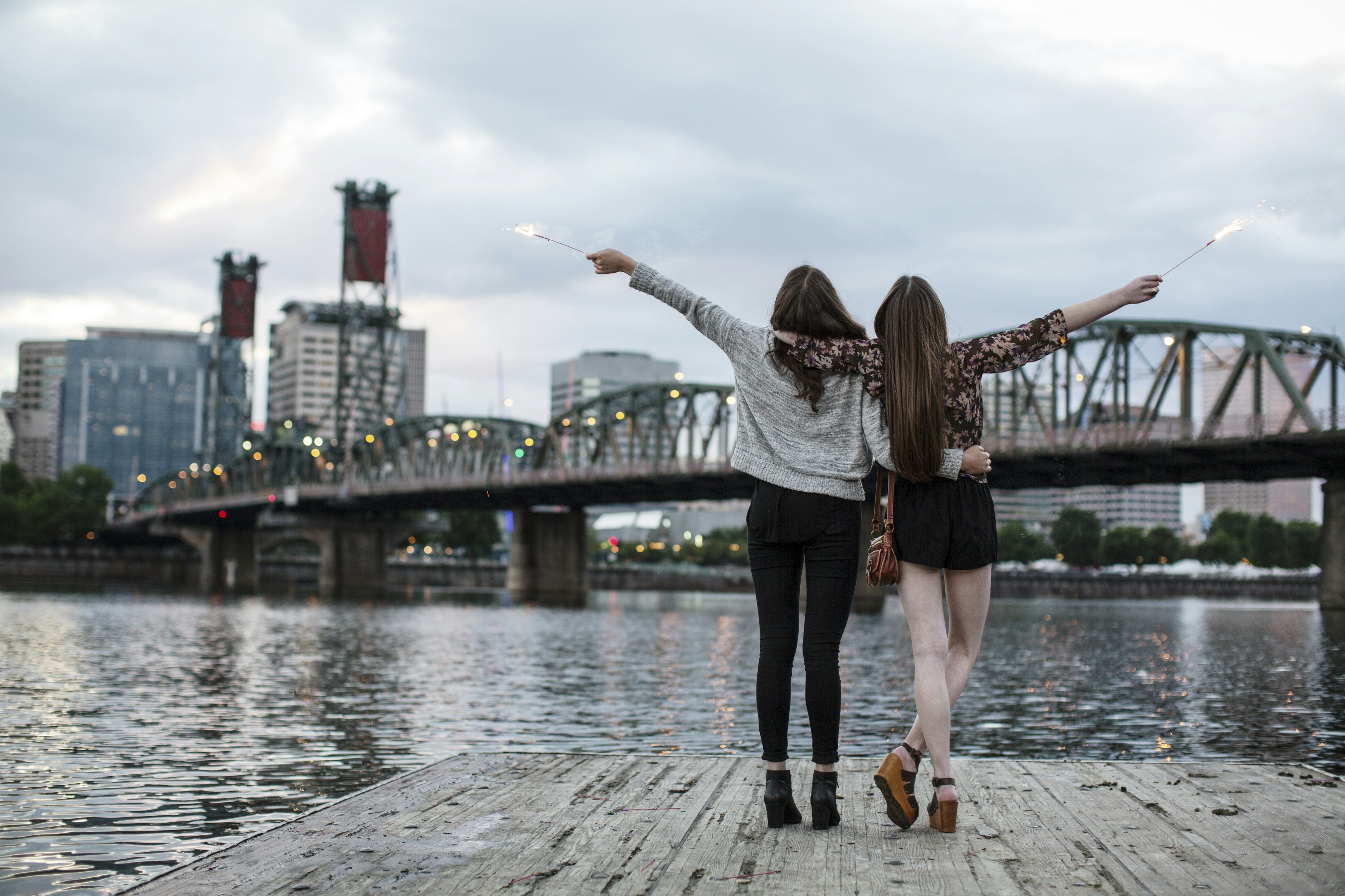 Female friends burning firework while standing against Burlington Northern Railroad Bridge 9.6