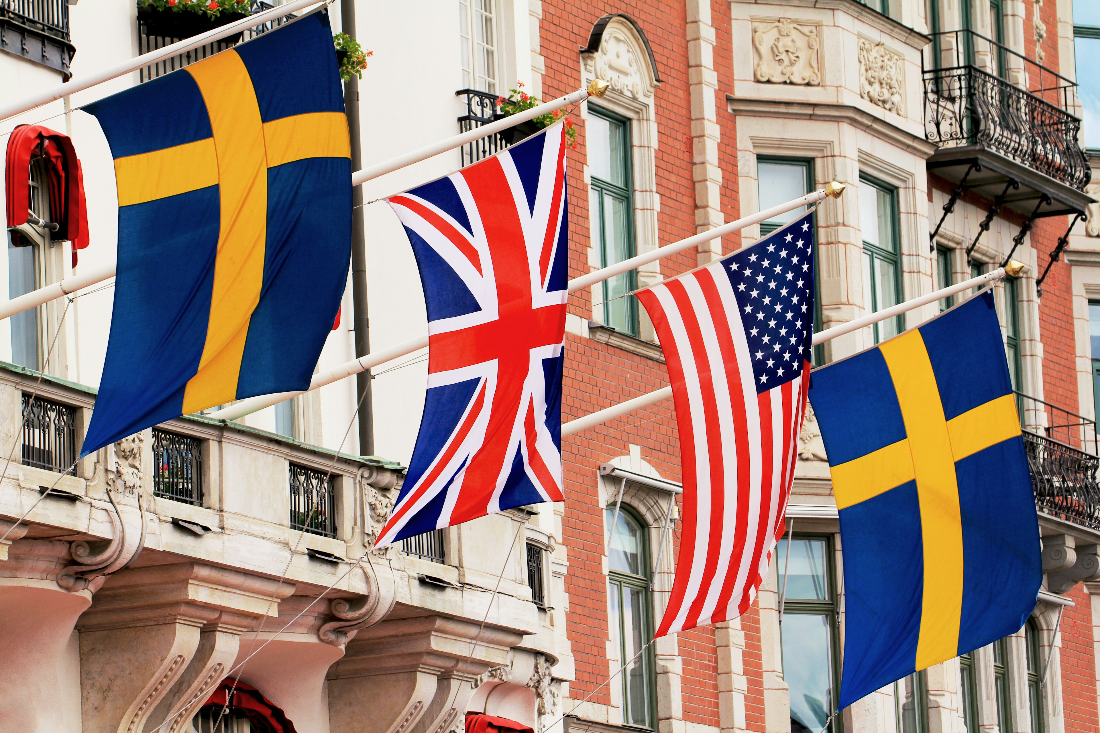 Sweedish, UK and American flags hanging in front of buildings