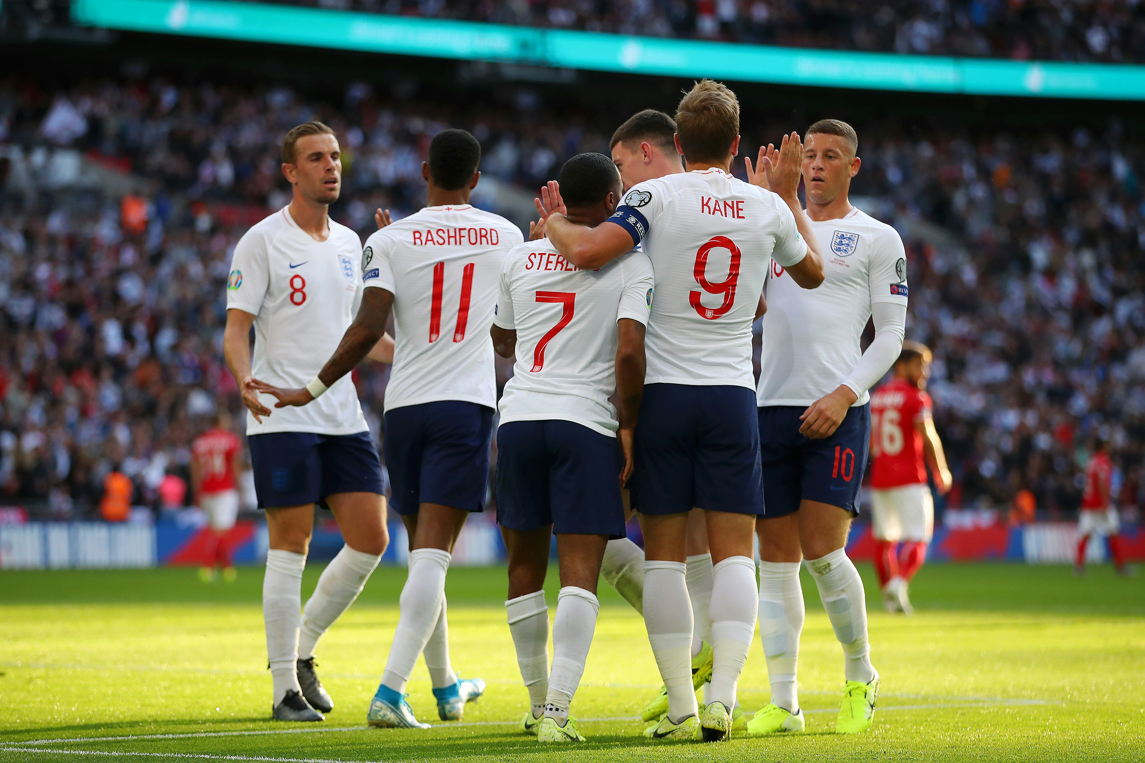 Members of the England football team high-fiving on the pitch after a game.