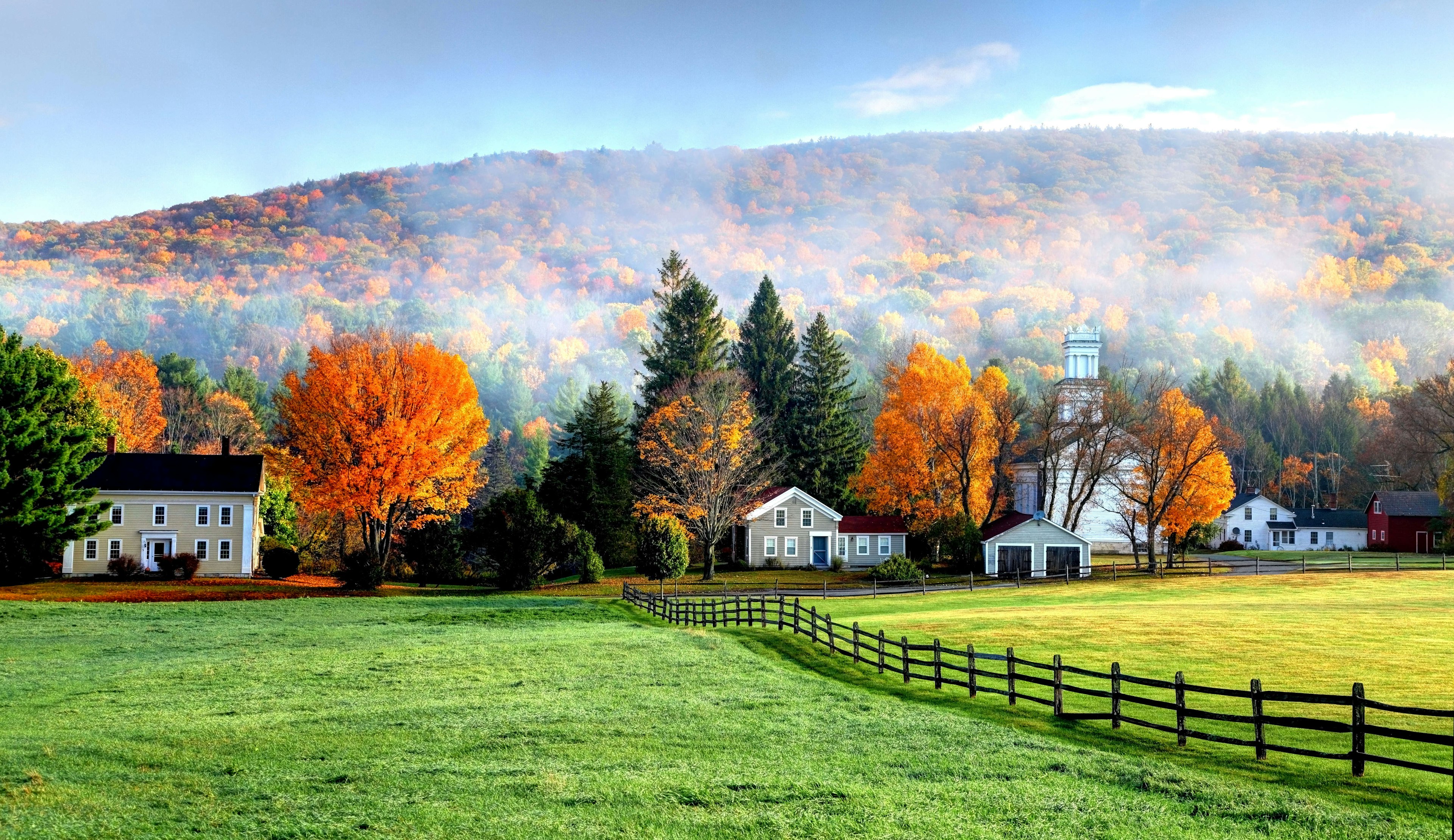 White farmhouses sit among the autumn leaves.