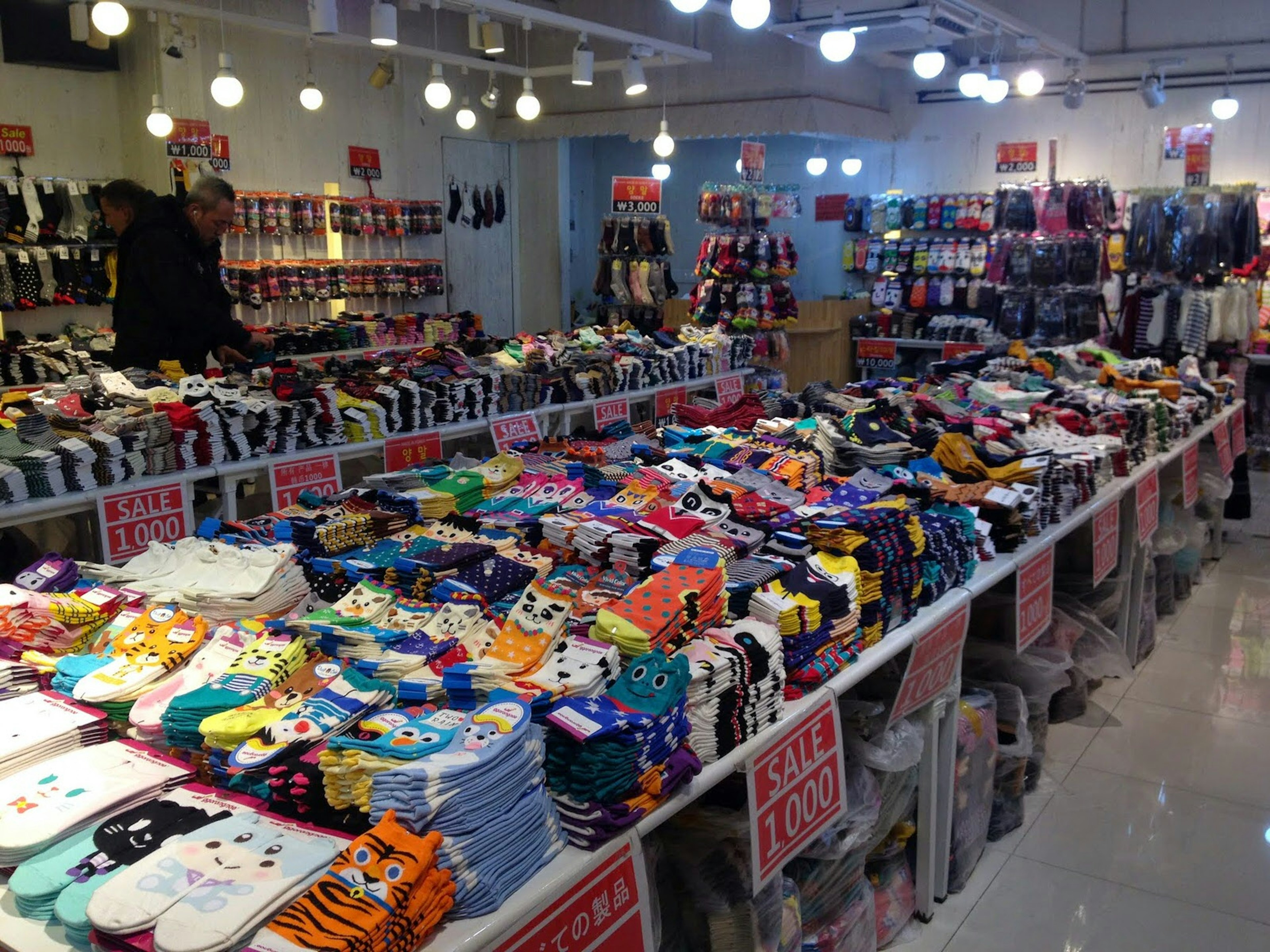 A large sock store with piles of socks on several tables and hanging on the walls