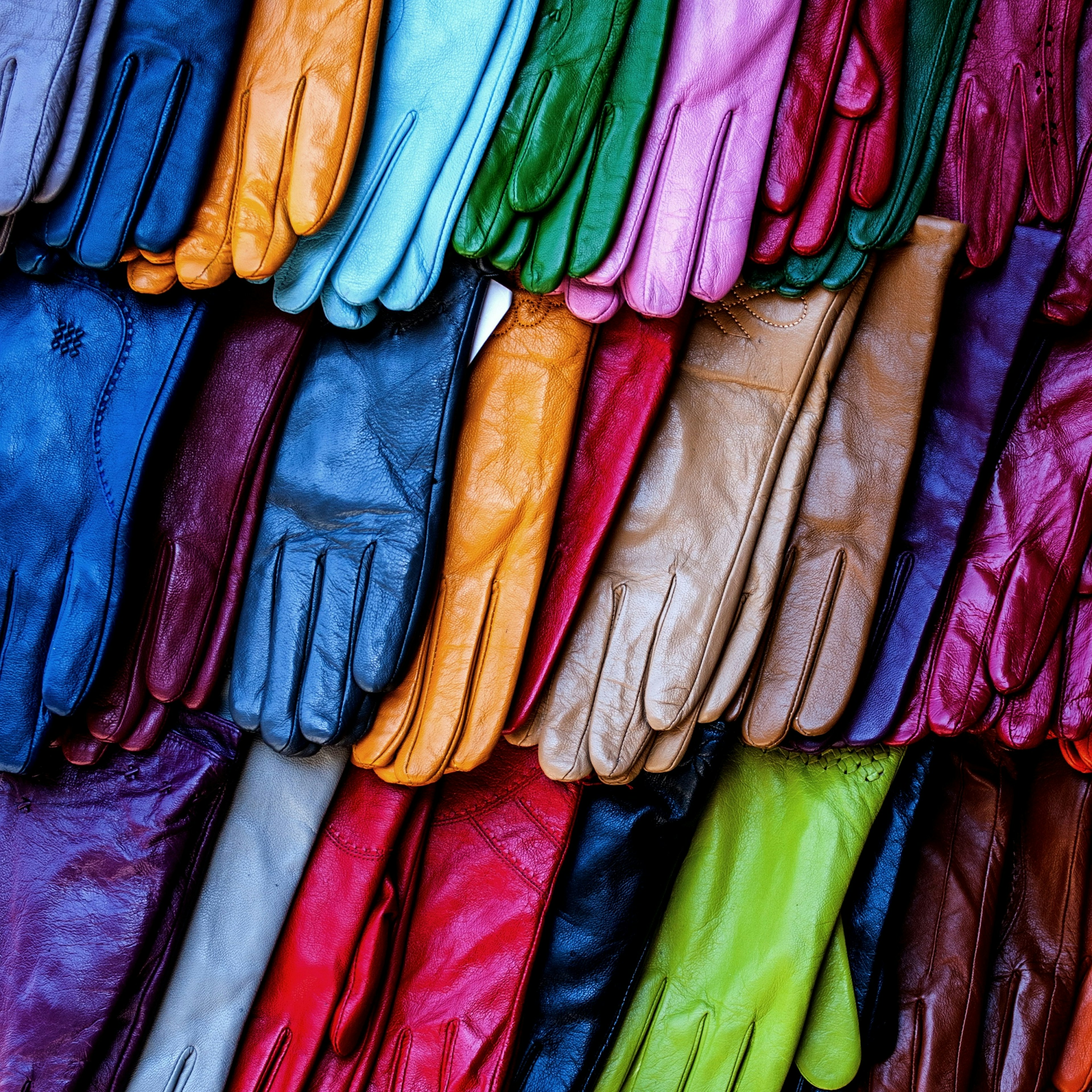 A series of brightly colored leather gloves on display