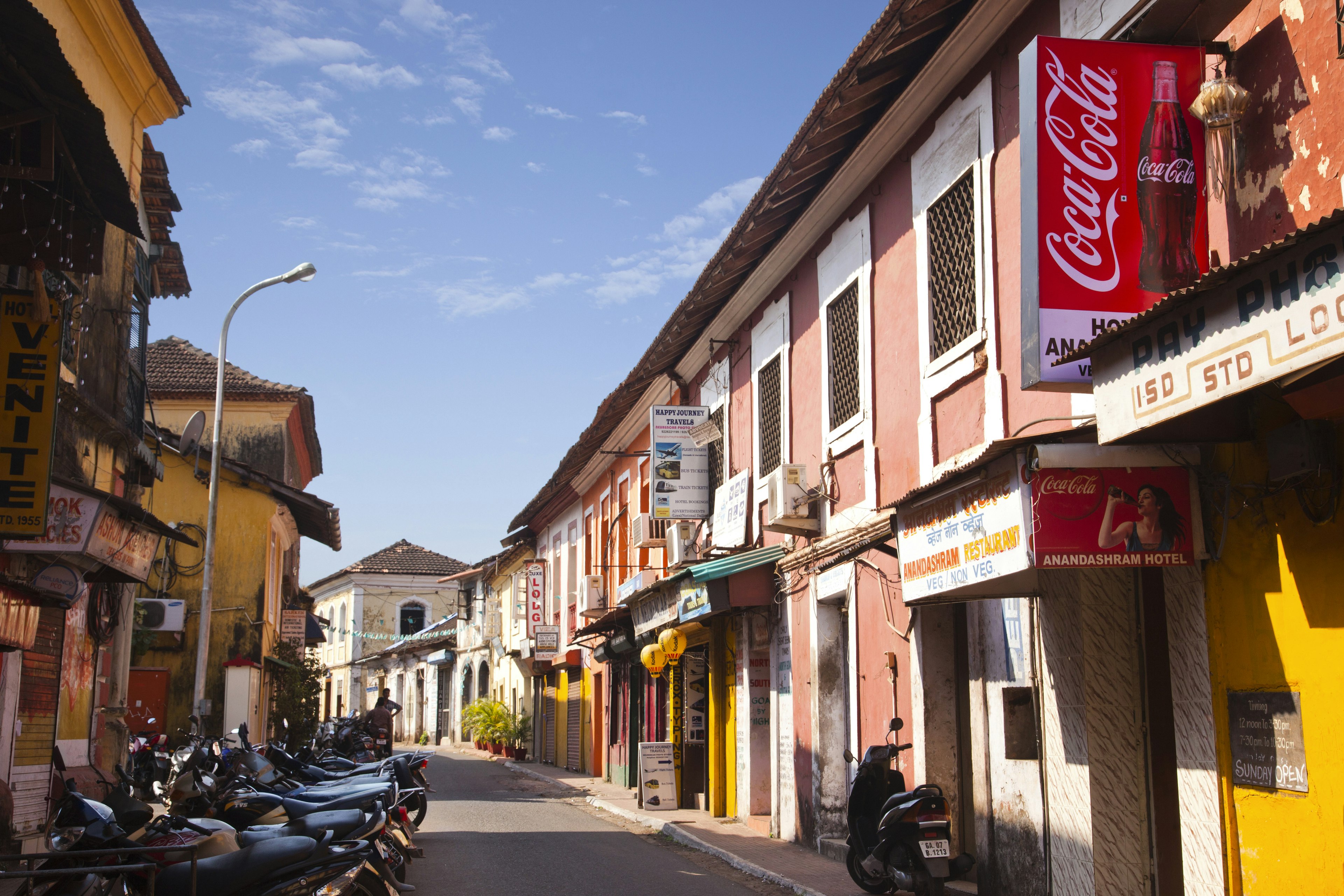 The pink and ochre stucco buildings line a winding street in Goa