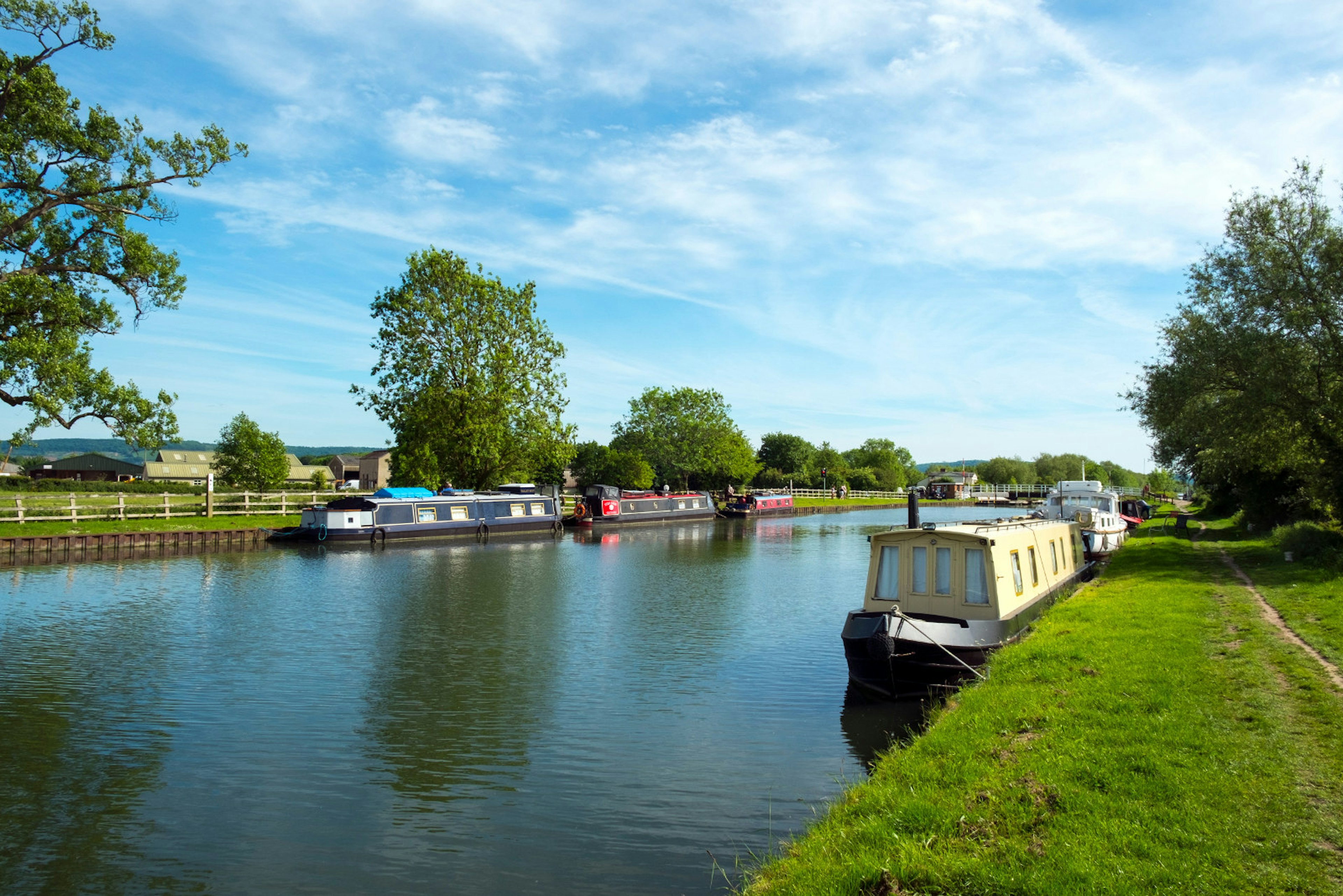 Canal boats moored on a river on a sunny day.