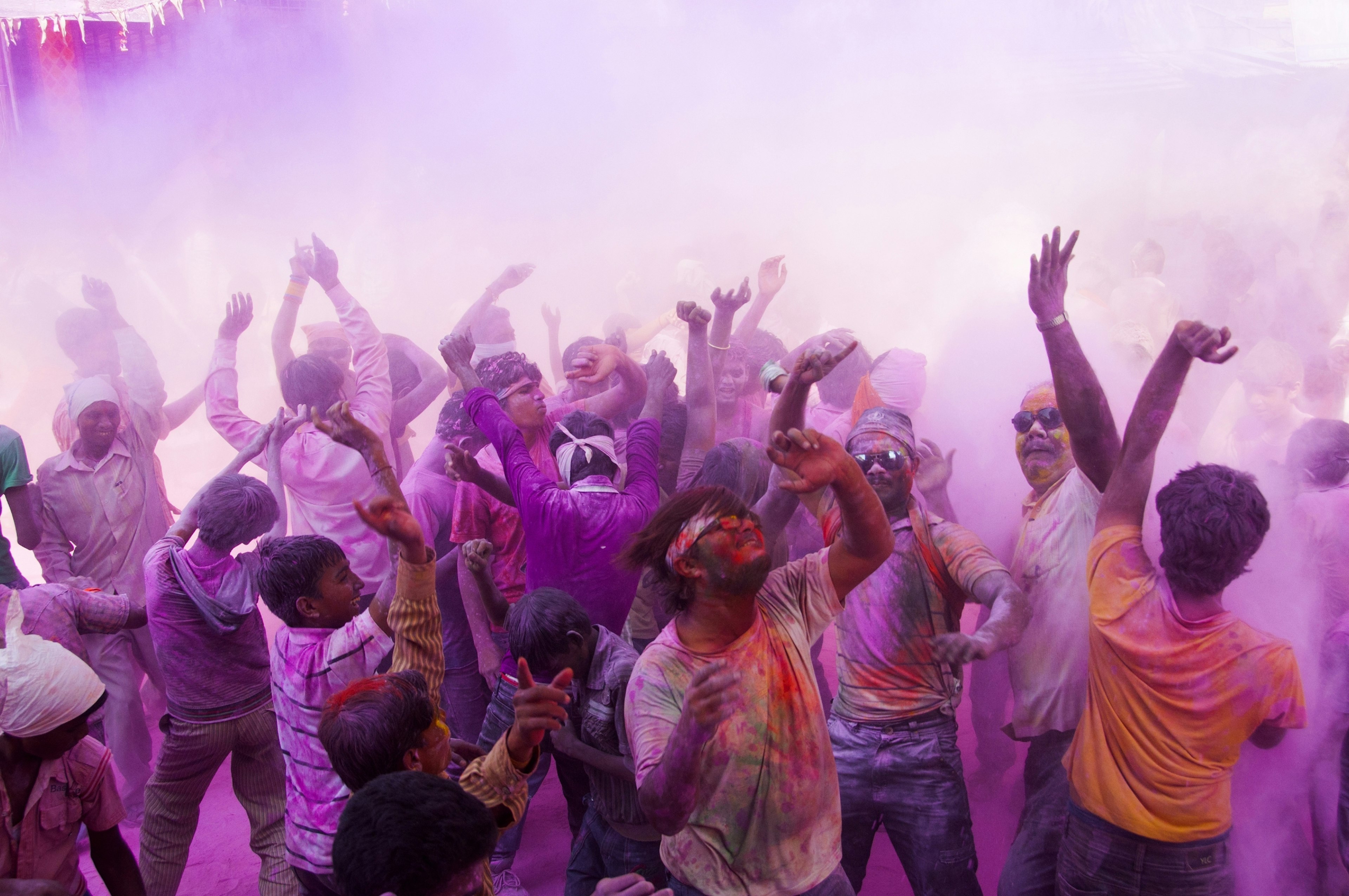 Crowd of men dancing while covered in purple powede