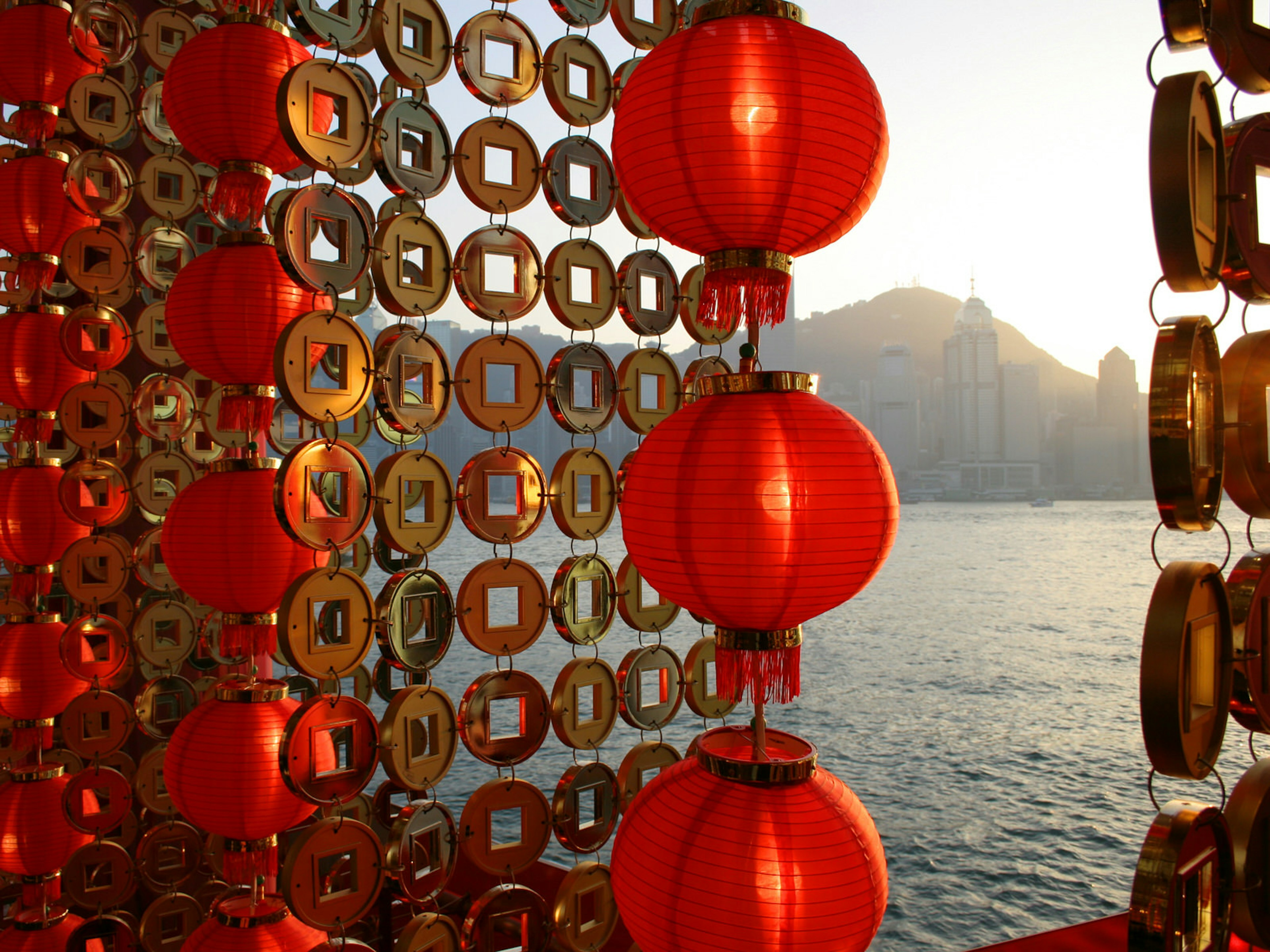 Red Chinese New Year lanterns and gold-coin decorations along Victoria Harbour © Gabrielle Chan / Shutterstock