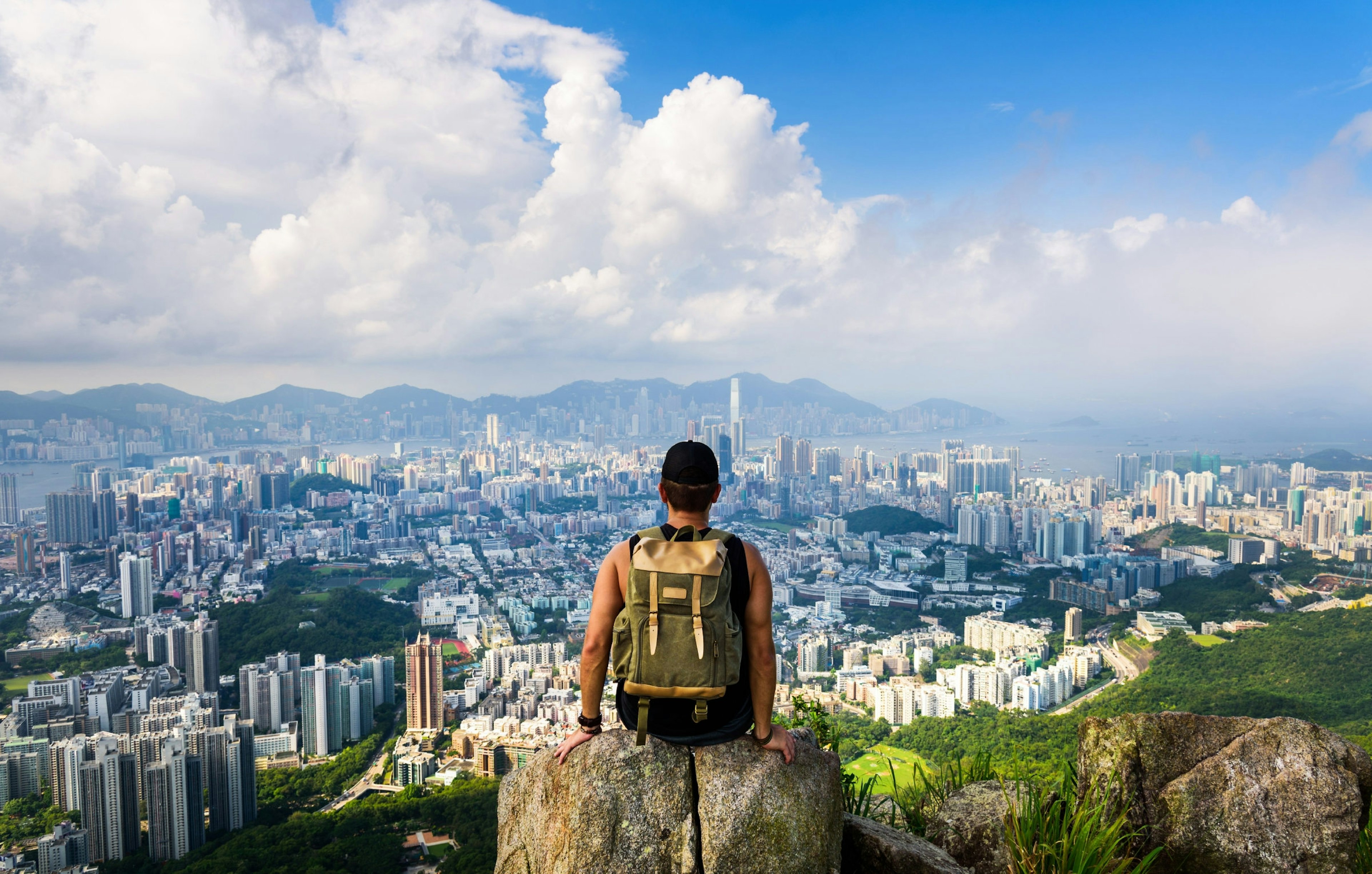 Man on Lion Rock lookout with the city of Hong Kong below