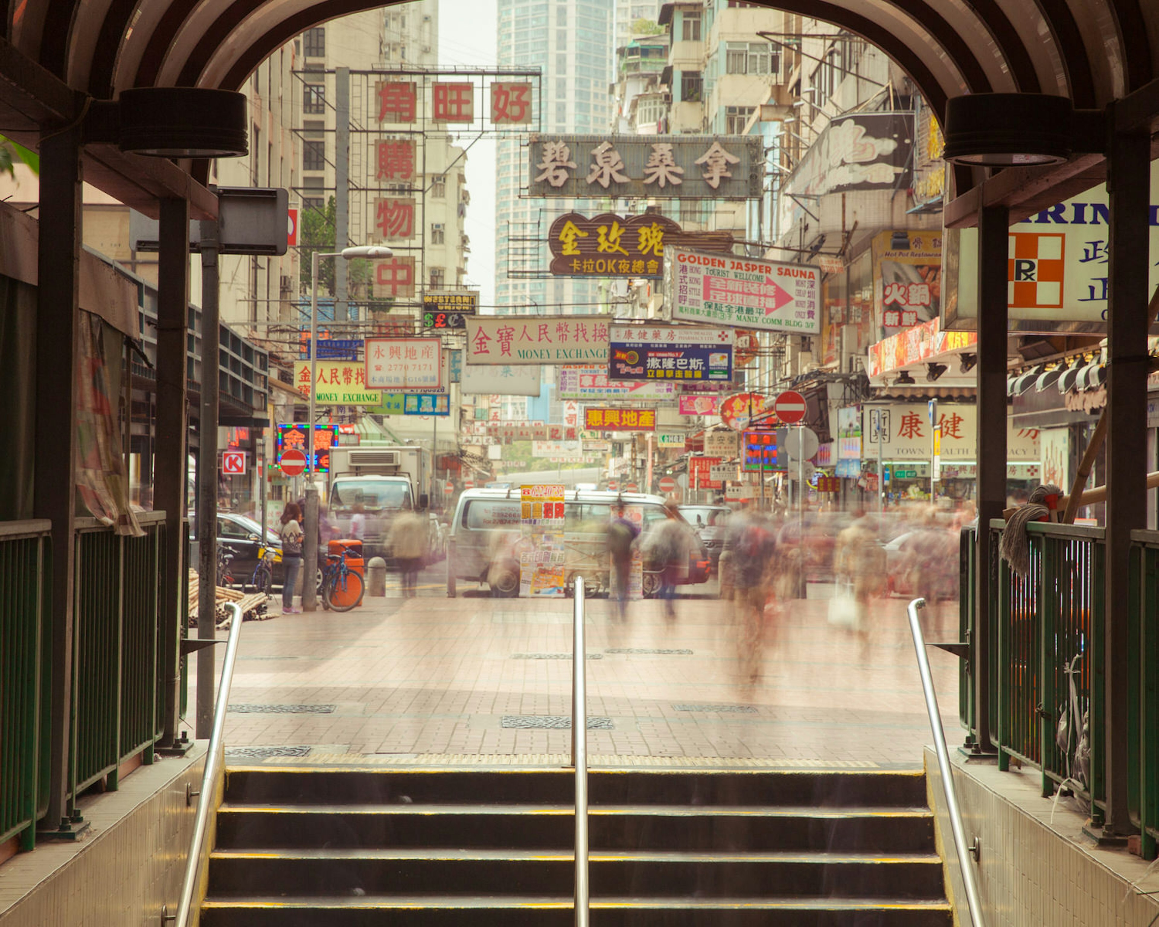 Blurred motion of people going down the stairs of underground crossing with numerous Chinese signs in the background