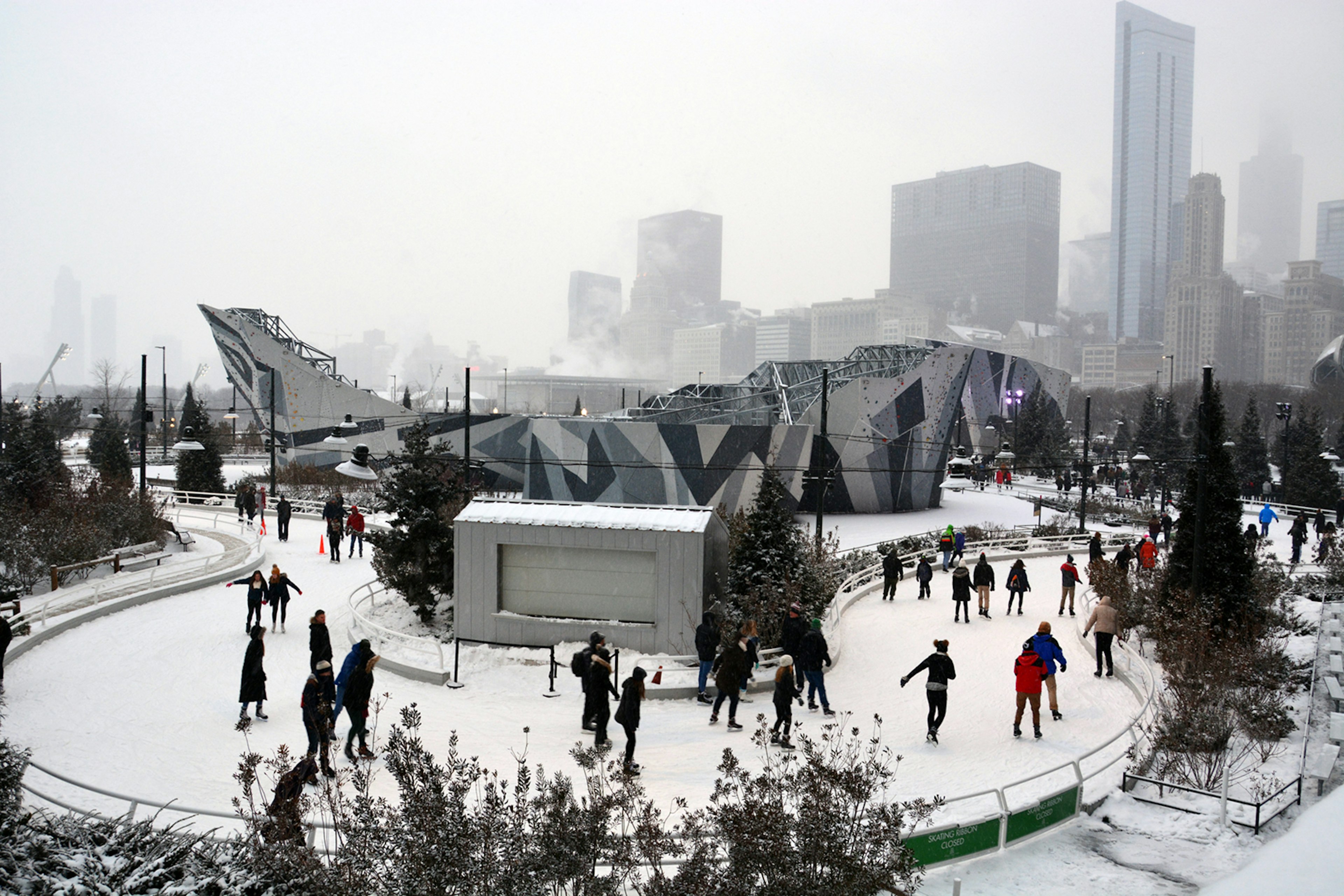 bundled-up skaters brave the ice on the skating ribbon in Chicago on an overcast day