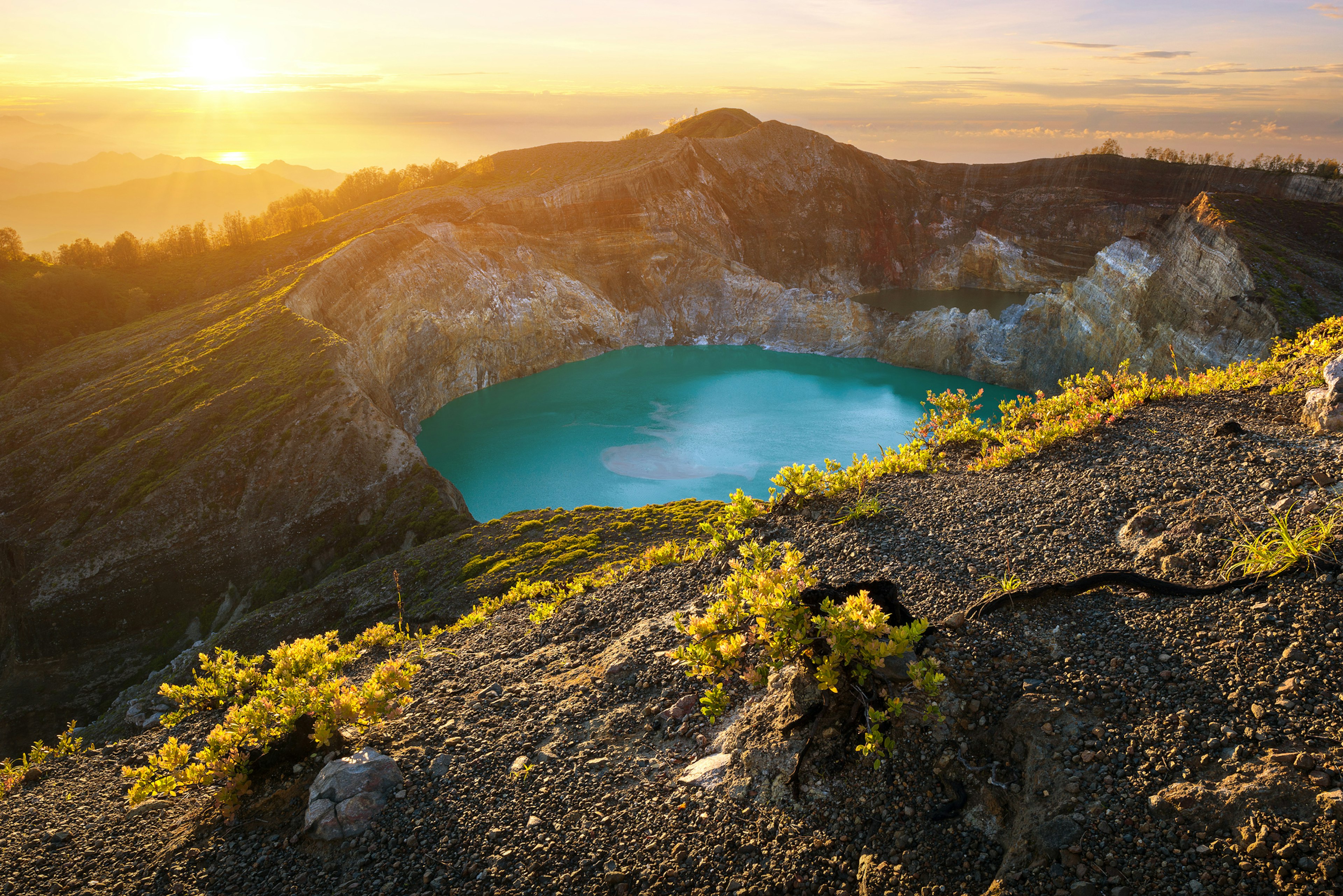 A volcanic crater is filled with blue water surrounded by a mountain.