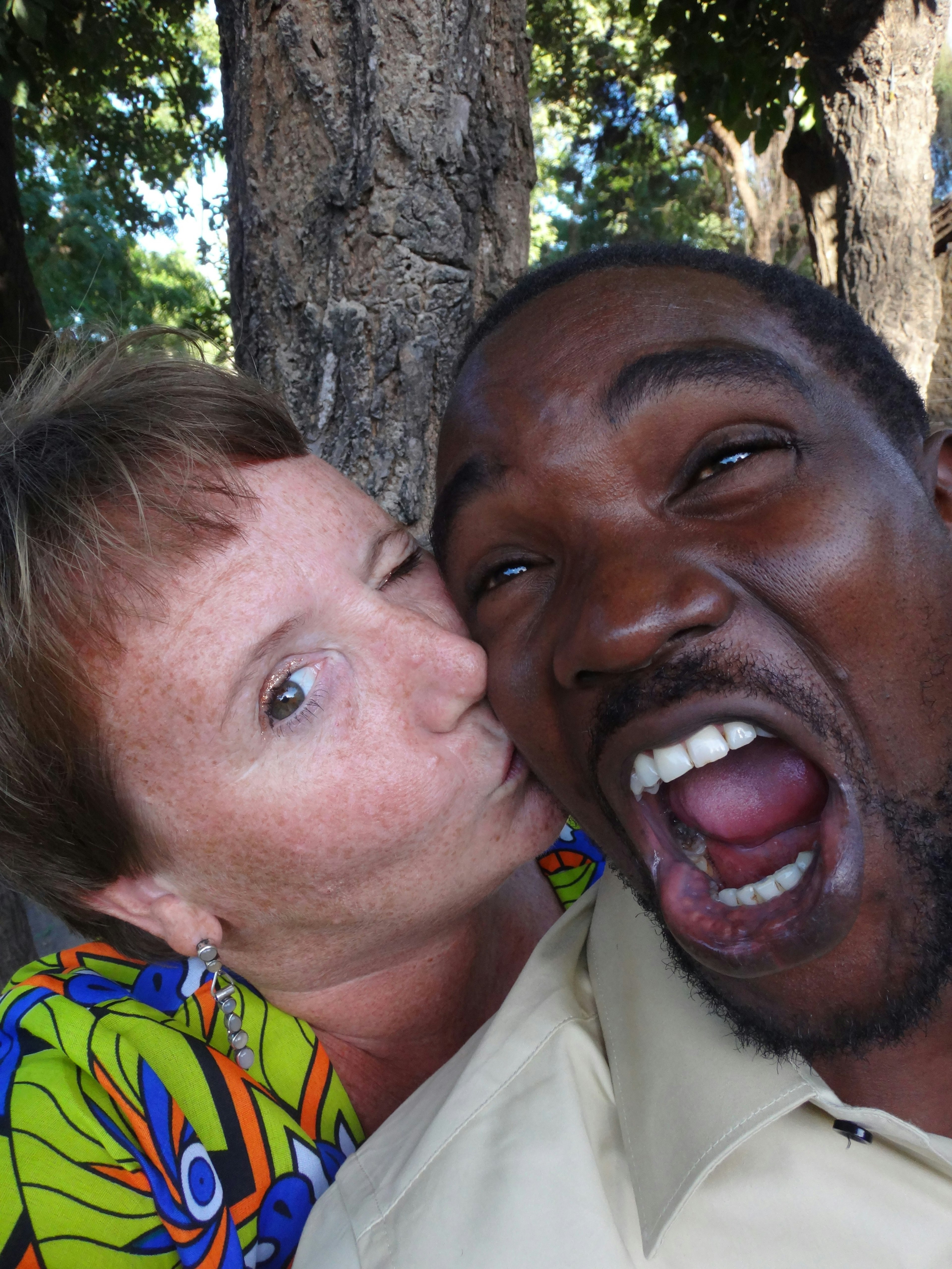 Jennifer Gilmore and her partner Fabi Mwaikokoba pose for the camera in front of a woodland scene.