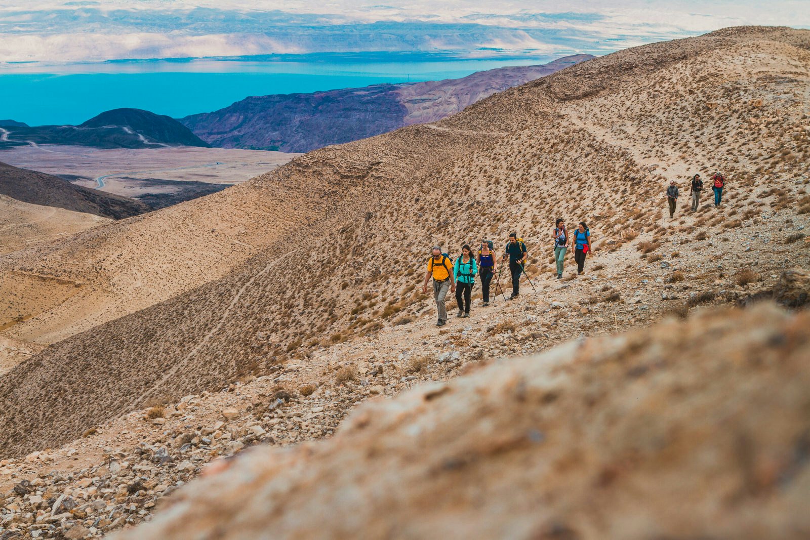 Hikers follow a track in a hilly desert landscape