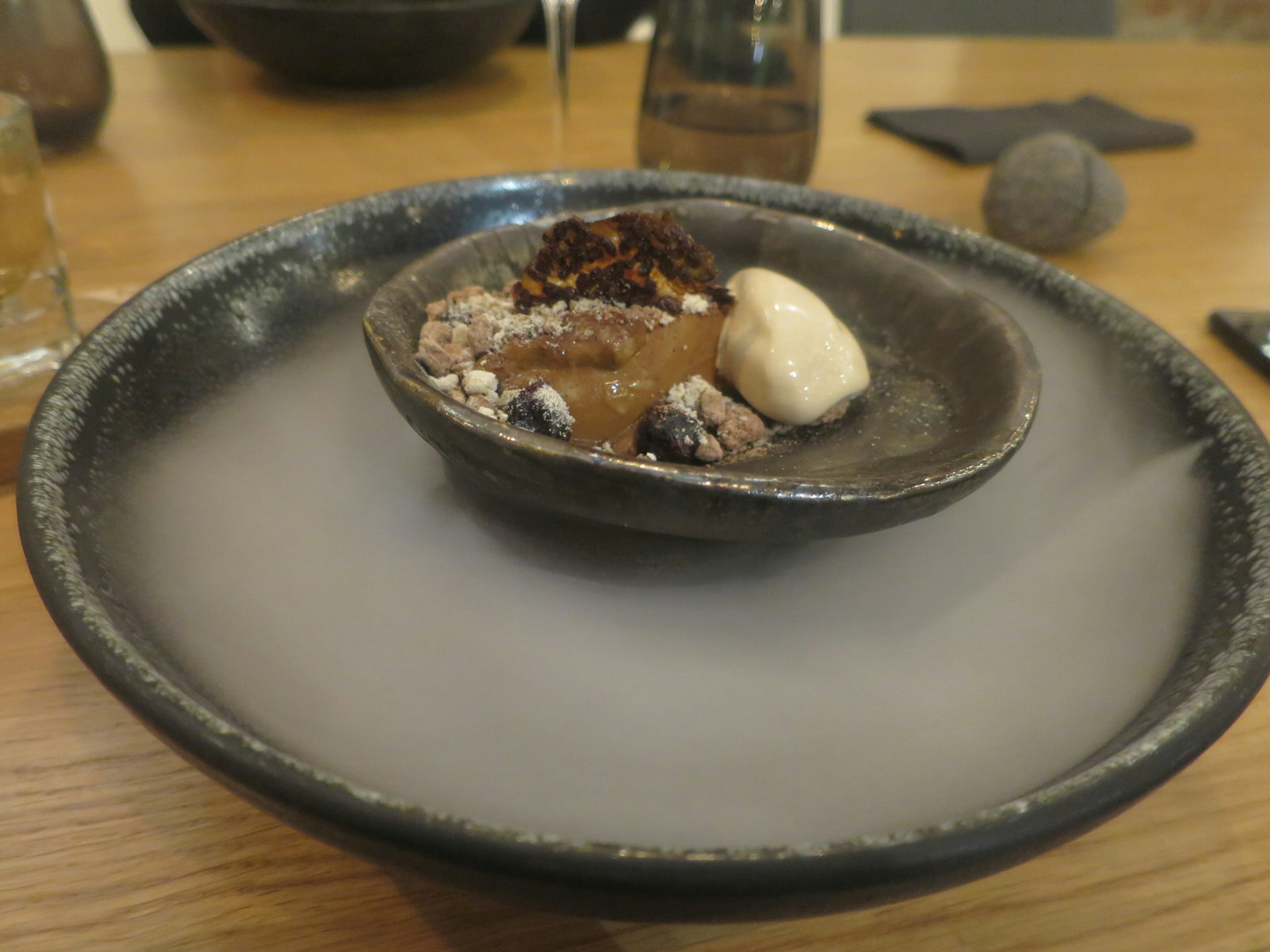 The 'Bread Dessert' at Tallin's Juur restaurant consists of blackcurrants, flax seed crisp and chaga tea ice cream, and liquid nitrogen smoke © Karyn Noble / iBestTravel