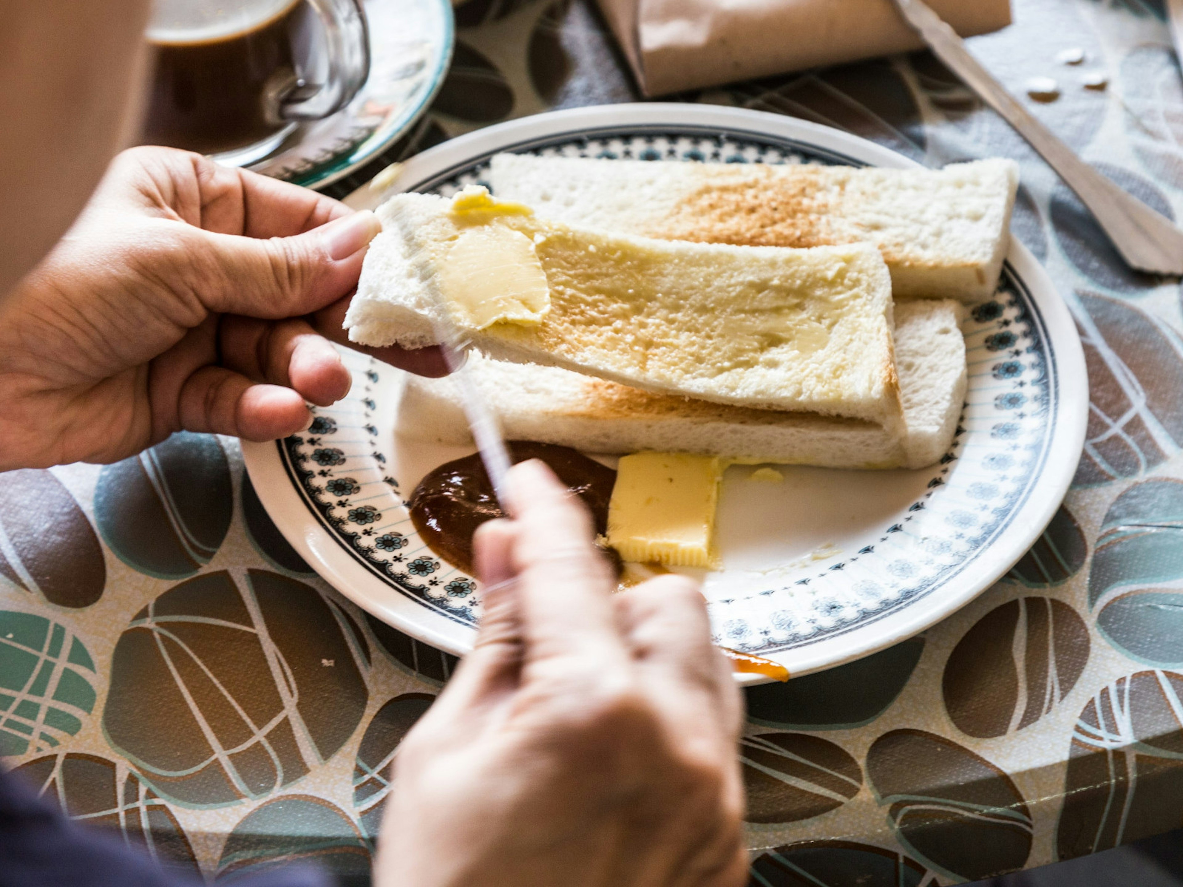 Applying butter and kaya to steamed bread for breakfast