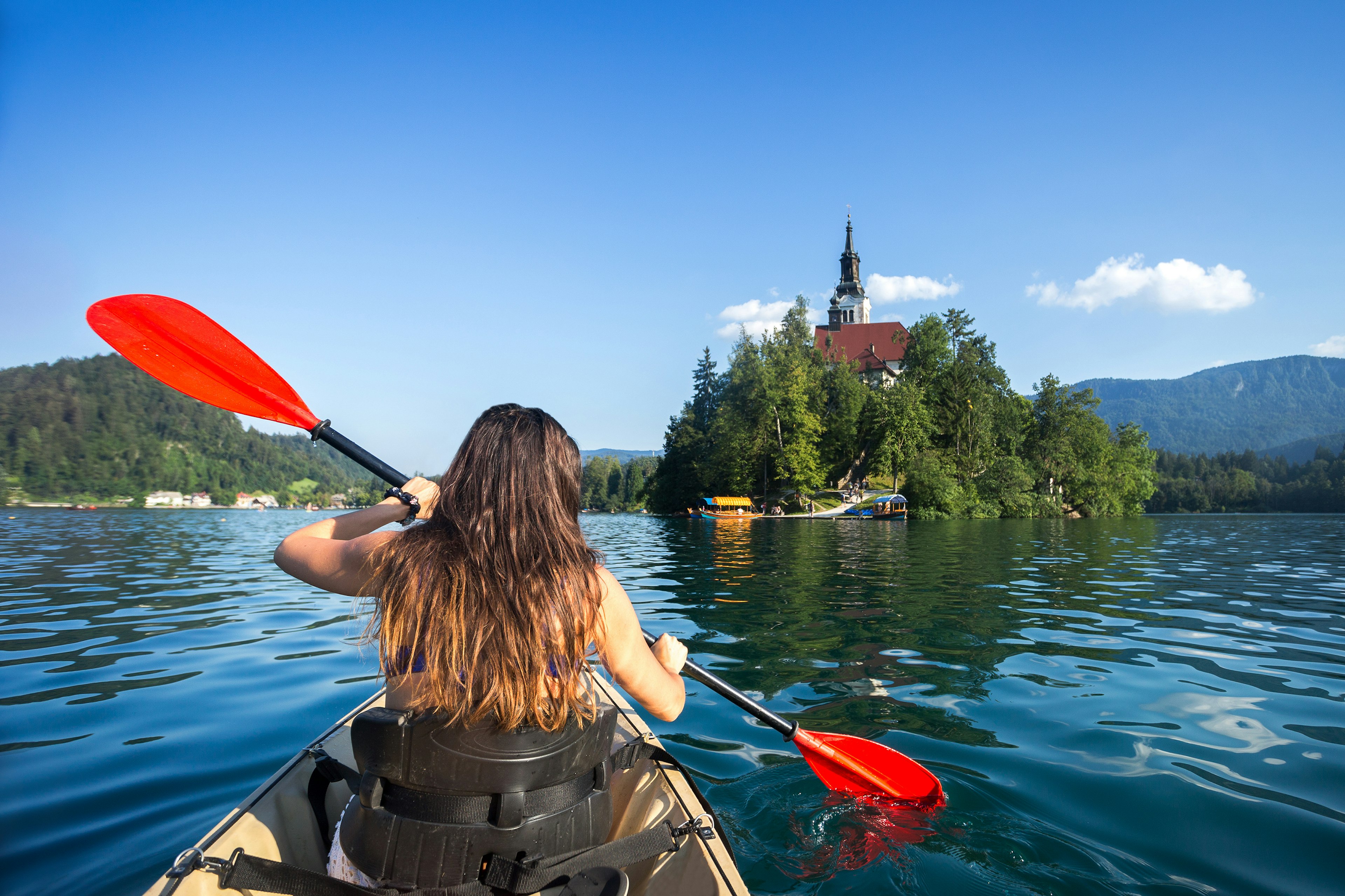 A woman kayaking across Lake Bled, Slovenia