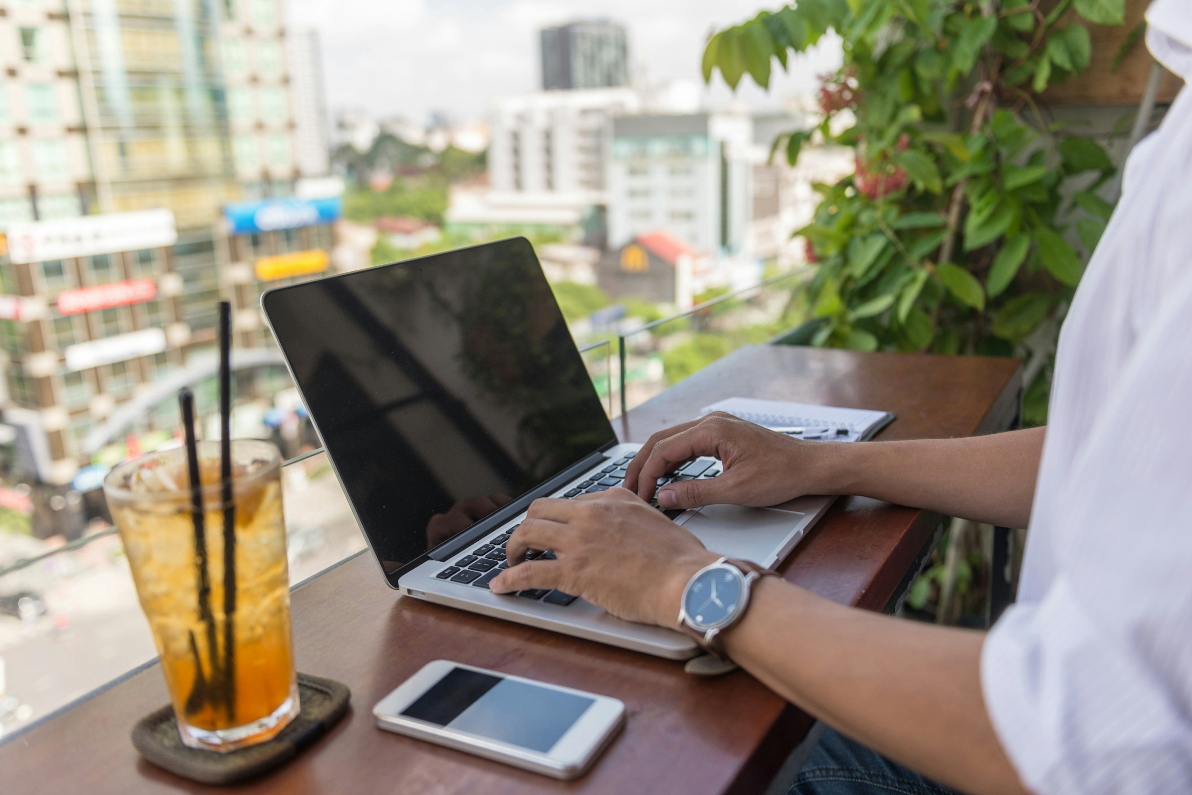 Person typing on a laptop overlooking a city street.