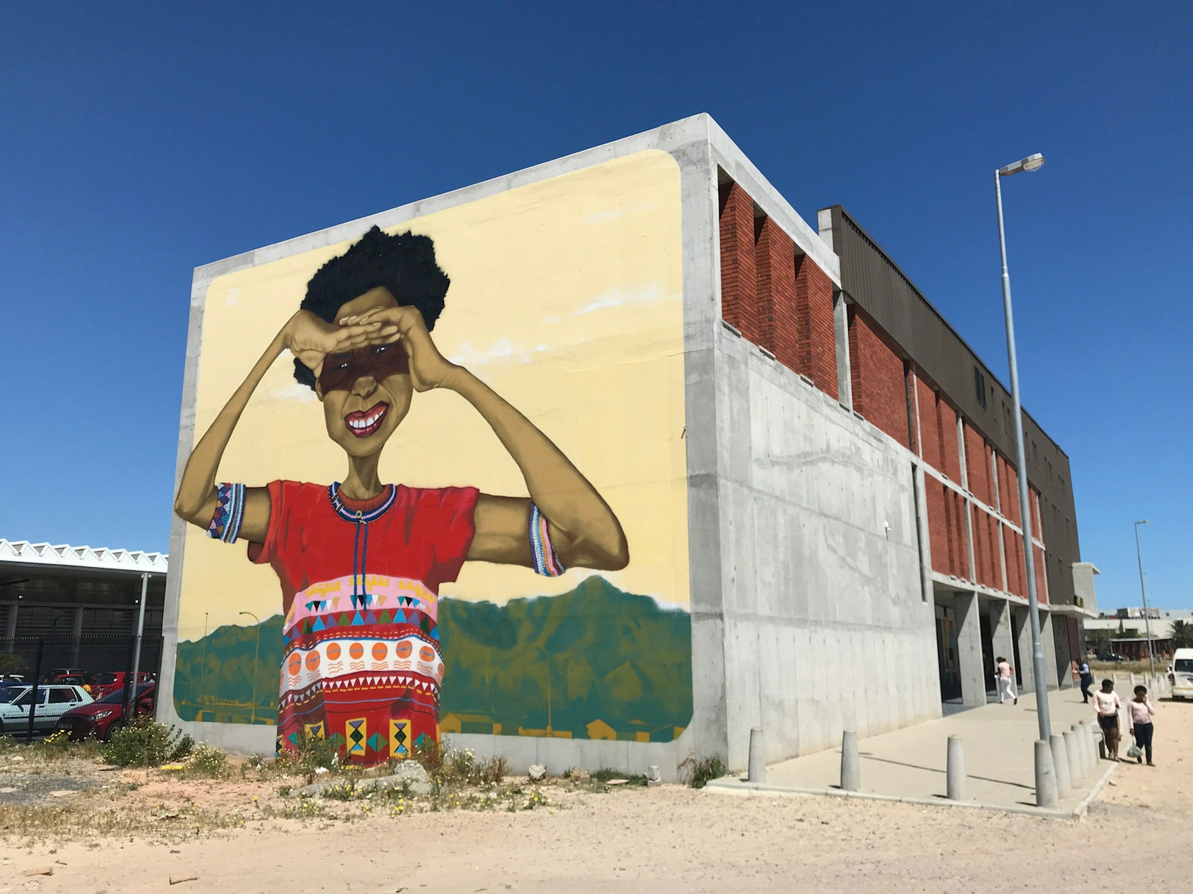 A massive mural of young black South African woman, with her arms raised to shade her eyes from the sun, stares out from the end of the Isivivana Centre's concrete facade © Simon Richmond / Lonely Planet