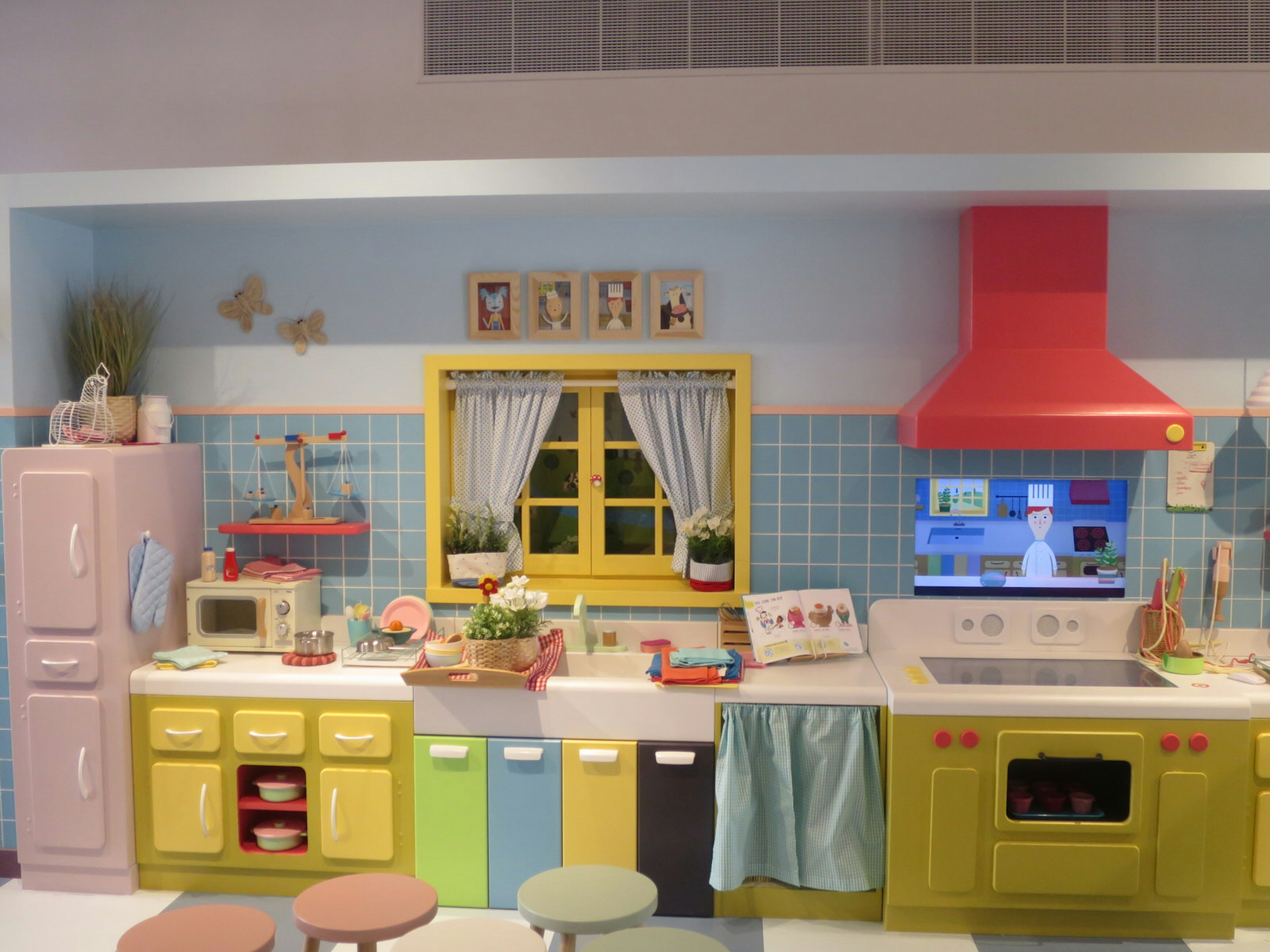 A colourful child-sized kitchen with an interactive screen to teach visitors how to make classic french dishes.