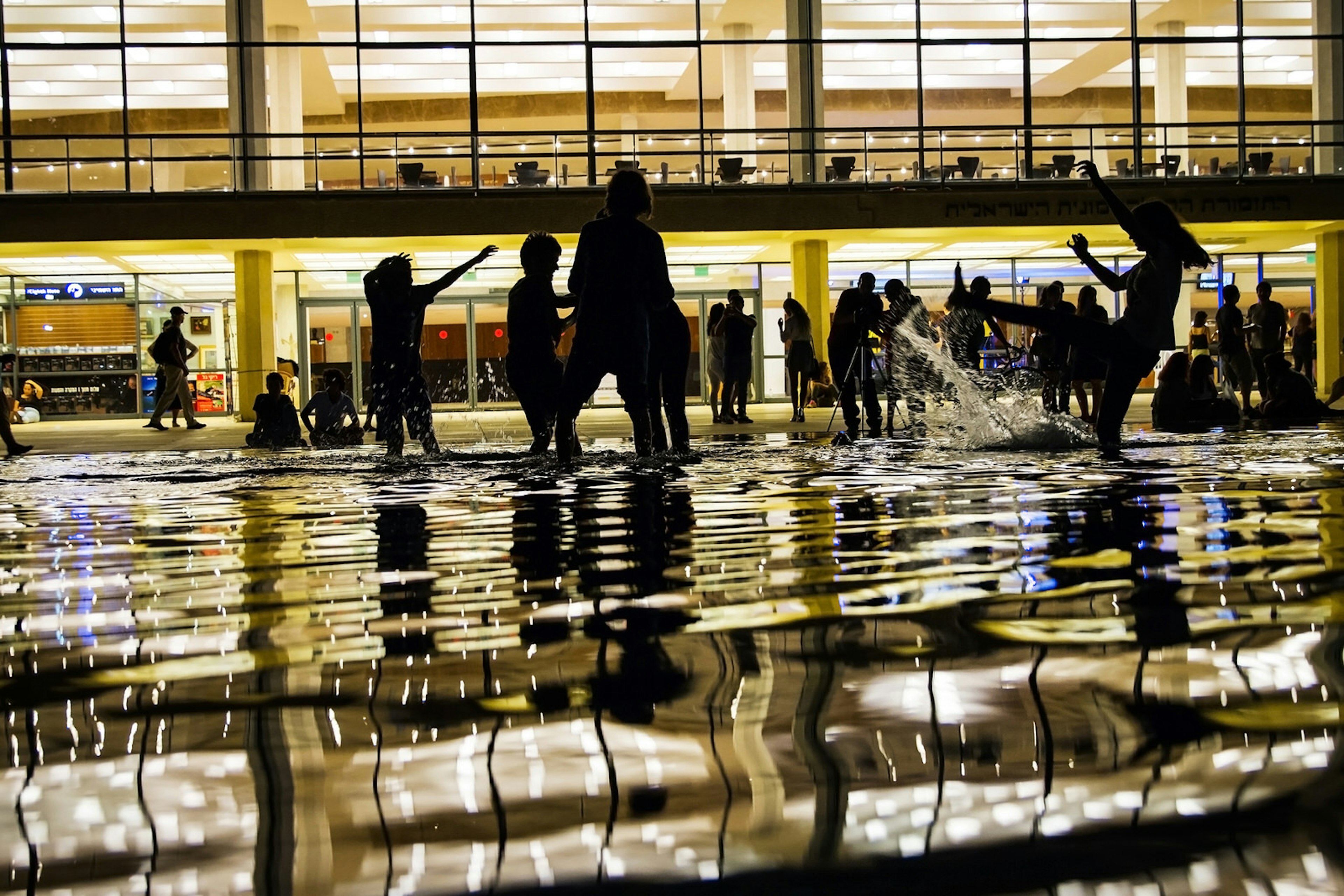 Silhouette children playing in water fountains at night, Tel Aviv, Israel