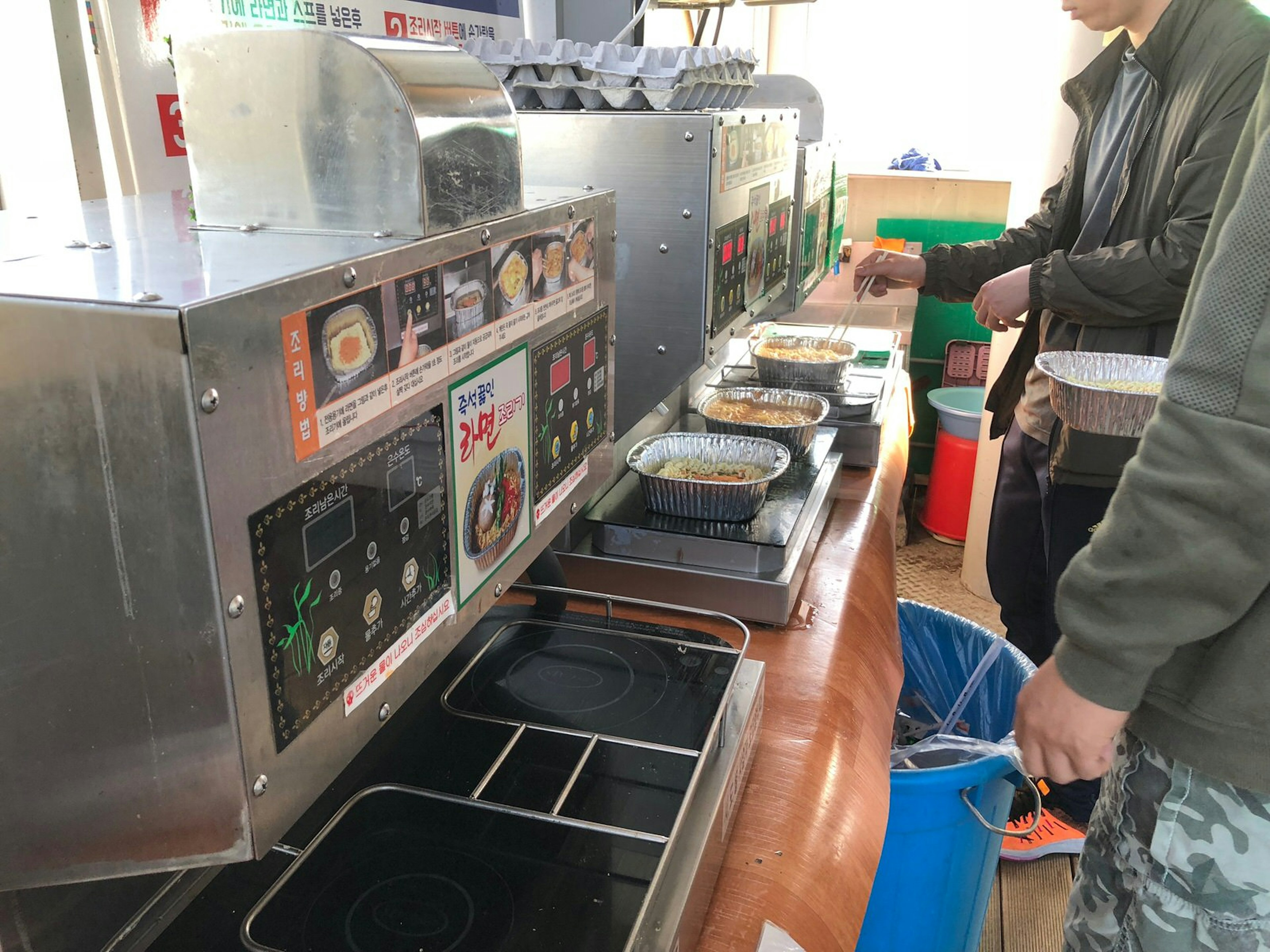 Patrons warm tins of instant noodles on burner machines. Instant noodles – ramen in Korea – are the most enduring convenience store snack food © Hahna Yoon / Lonely Planet