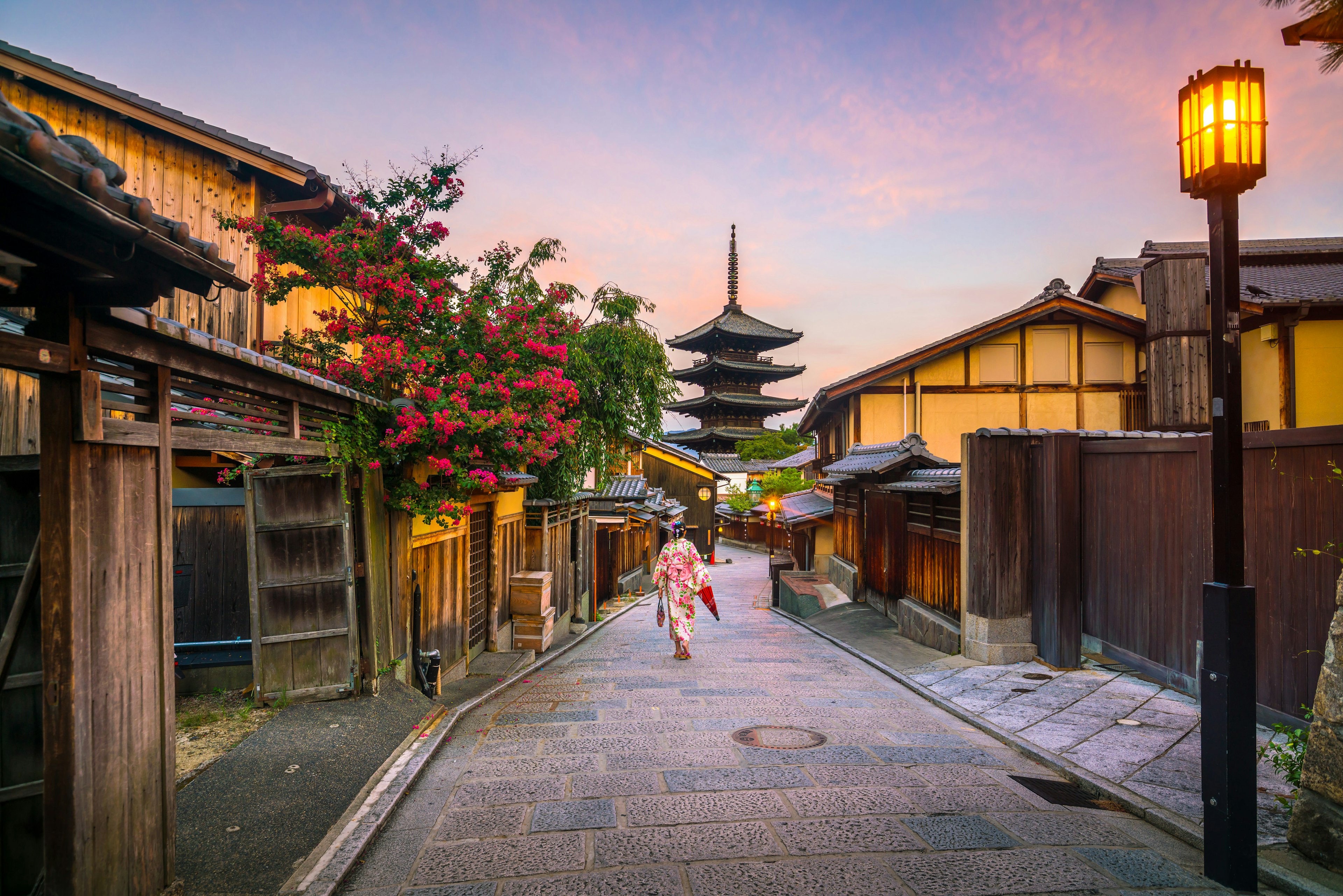 Japanese woman wearing a floral kimono walking through old town Kyoto, Japan