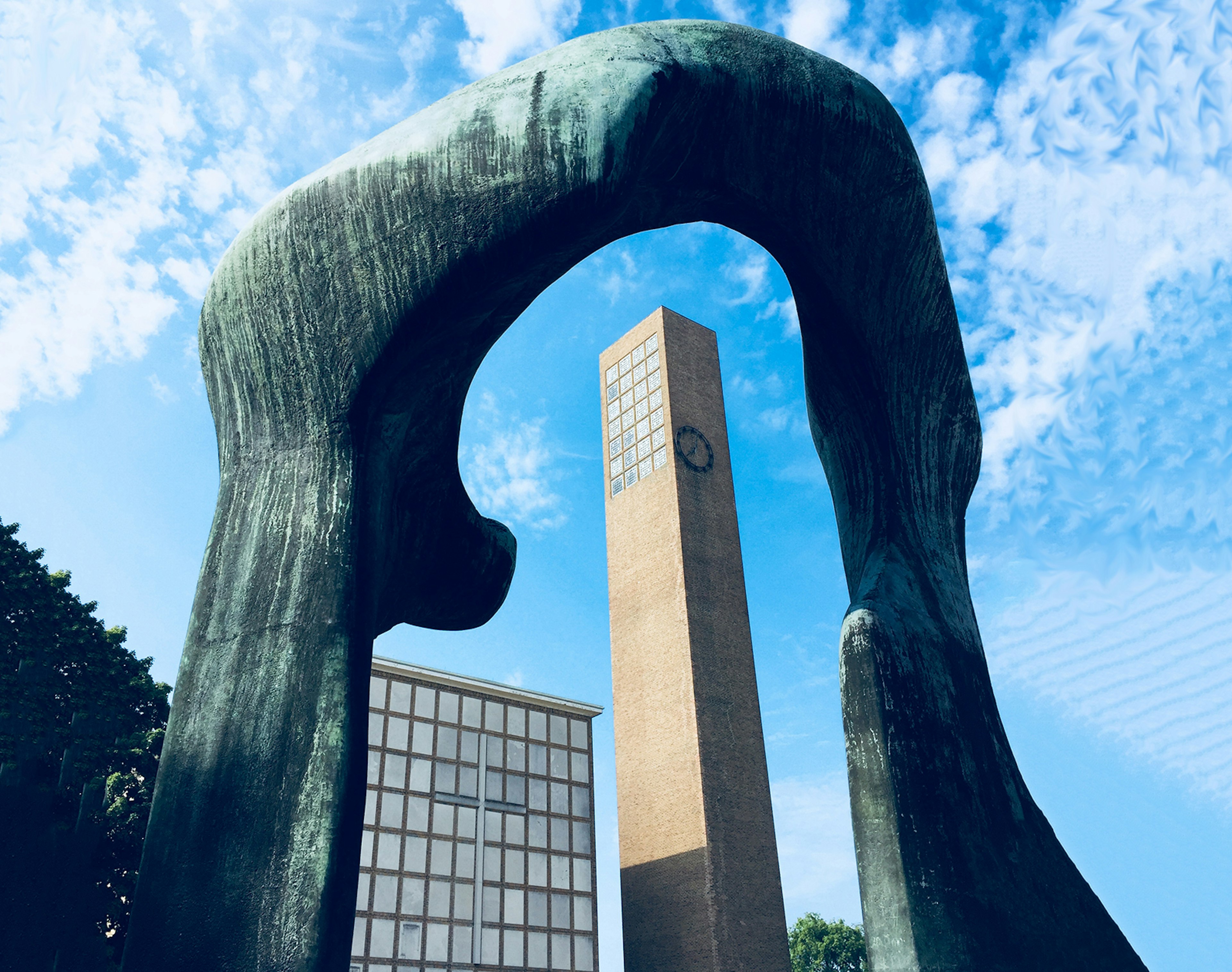 A mid-century modern church bell tower is framed by a blue abstract sculpture by Henry Moore in Columbus Indiana on a sunny day