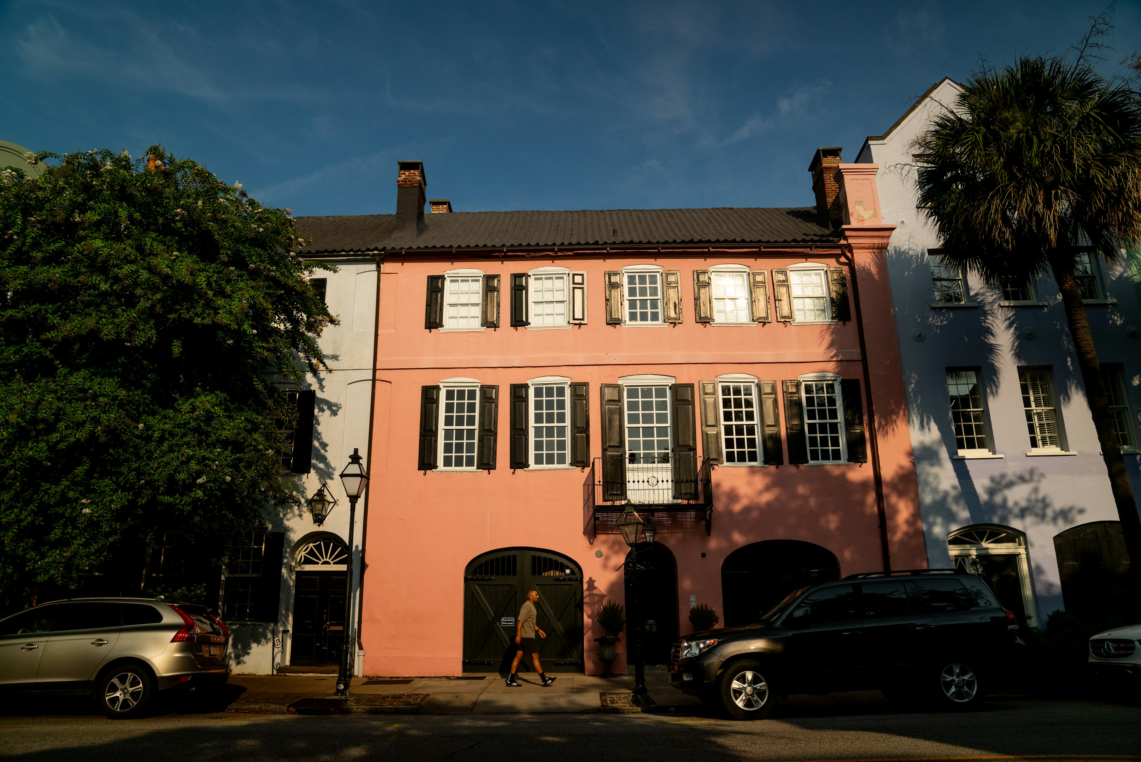 A man walks in front of a pink house on Rainbow Row, Charleston, SC