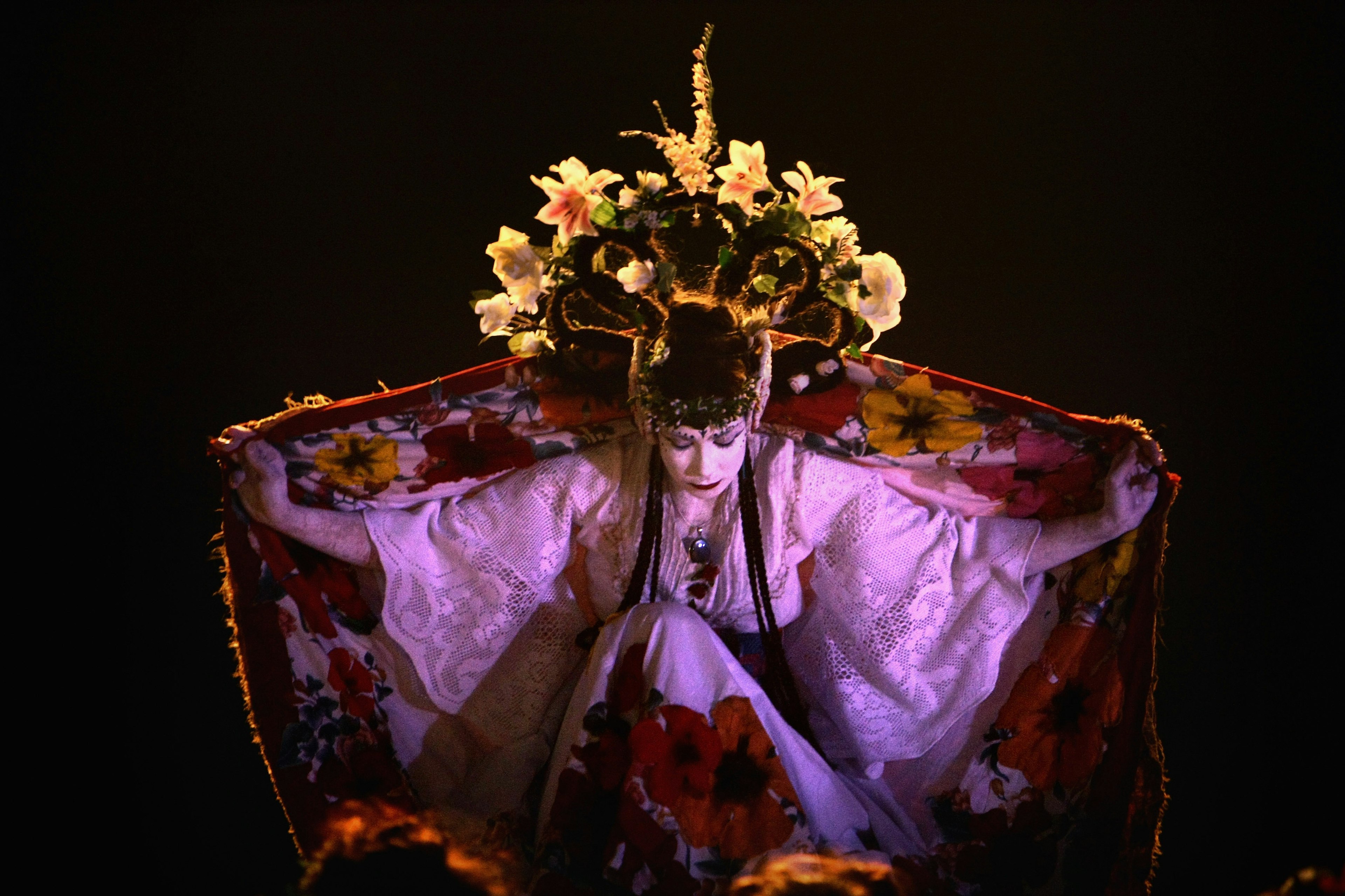 may-queen-beltane-fire-festival.jpgThe 2008 May Queen bows to her subjects wearing a crown of flowers and holding a floral shawl stretched out behind her like wings. She is wearing a white embroidered dress and her face is painted chalk white.