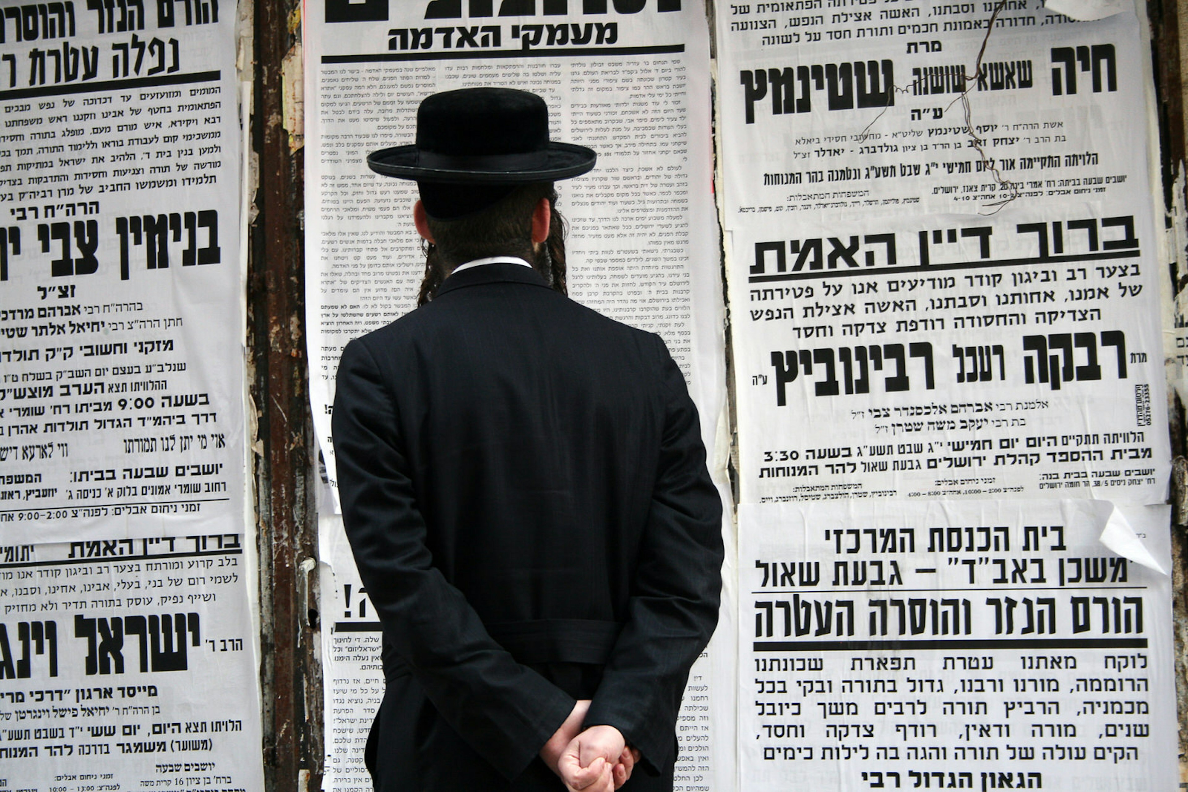 Man dressed in traditional clothing stands reading on the street in the ultra-orthodox area of Jerusalem, Mea Shearim