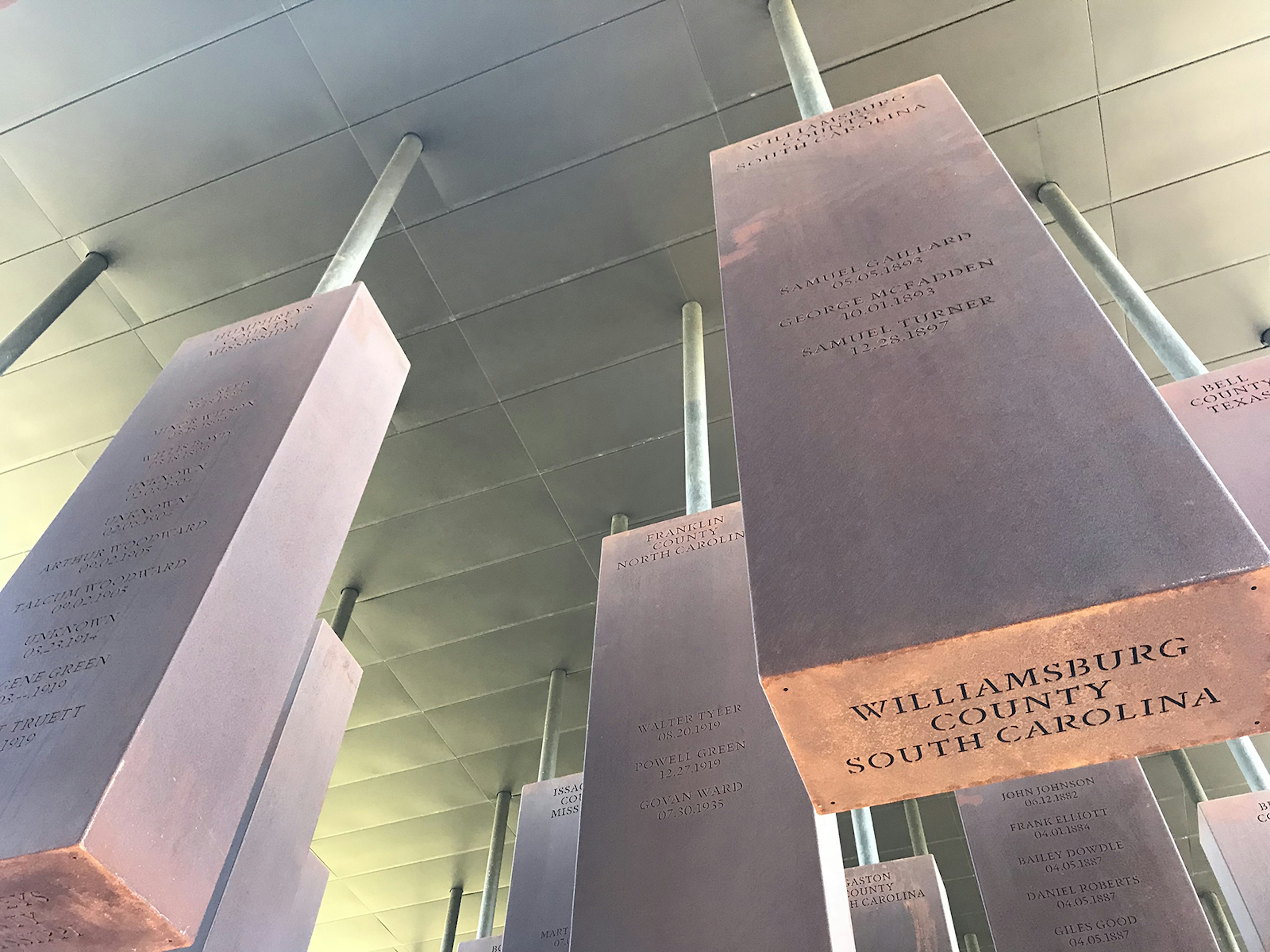 Steel columns hang from the ceiling of the Memorial to Peace and Justice. On one you can read the names of Samuel Gaillard, George McFadden and Samuel Turner, three men lynched in Williamsburg County, South Carolina © Carla Jean Whitley / ϰϲʿ¼