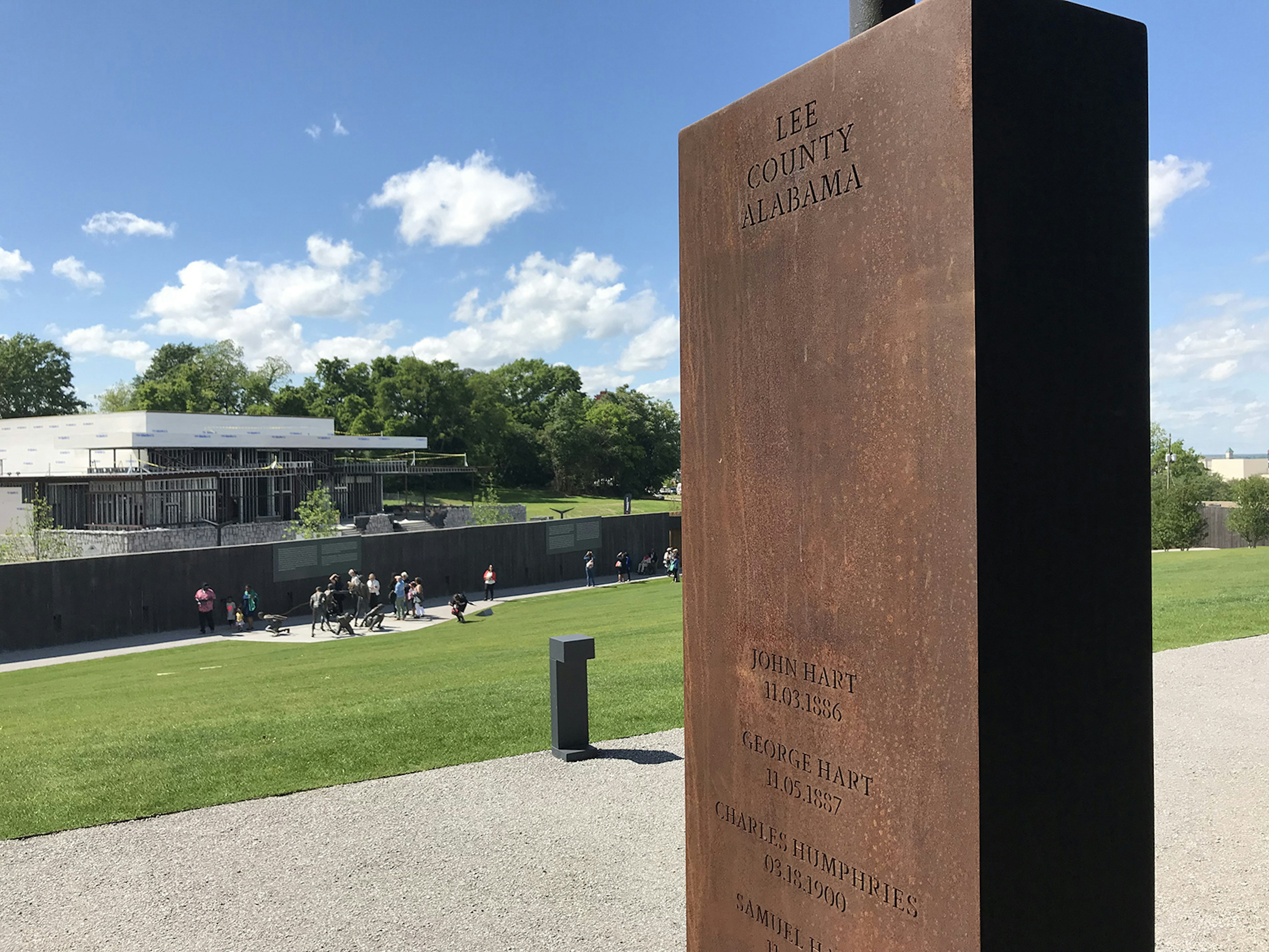 Close-up of steel pillar bearing the names of the people who were lynched in Lee County, Alabama. The National Memorial to Peace and Justice is in the background. © Carla Jean Whitley / Lonely Planet