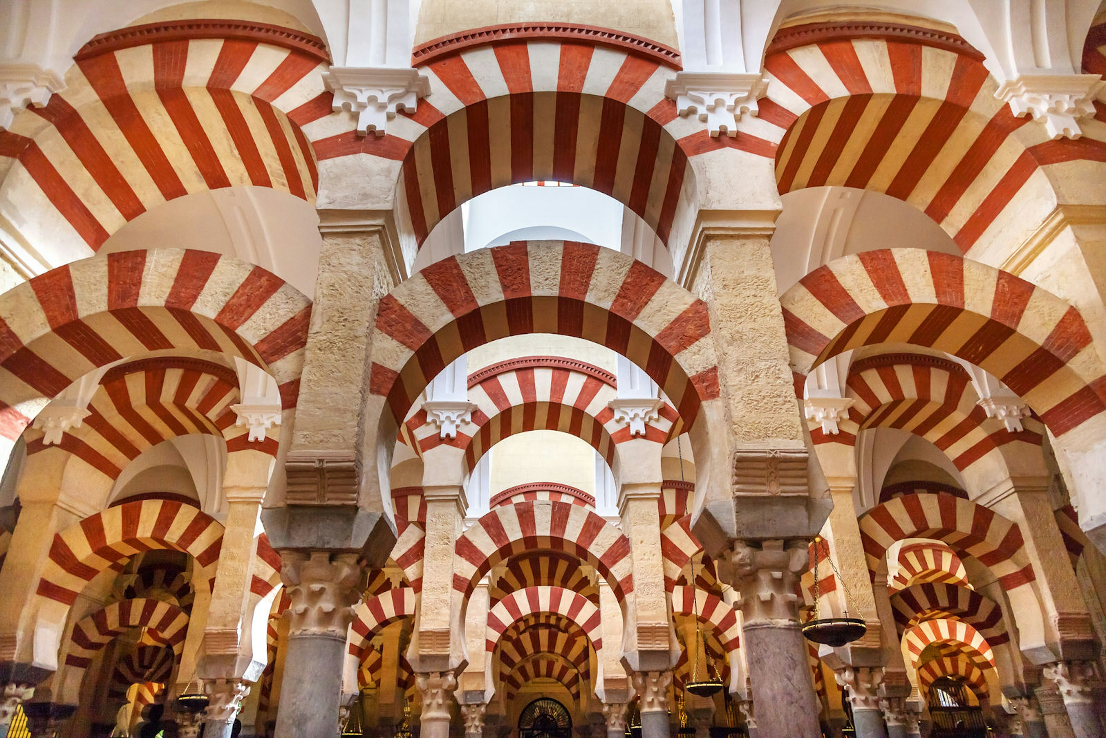 Inside Cordoba's Mezquita; the roof is supported by pillars and lines of arches striped in red brick and white stone.