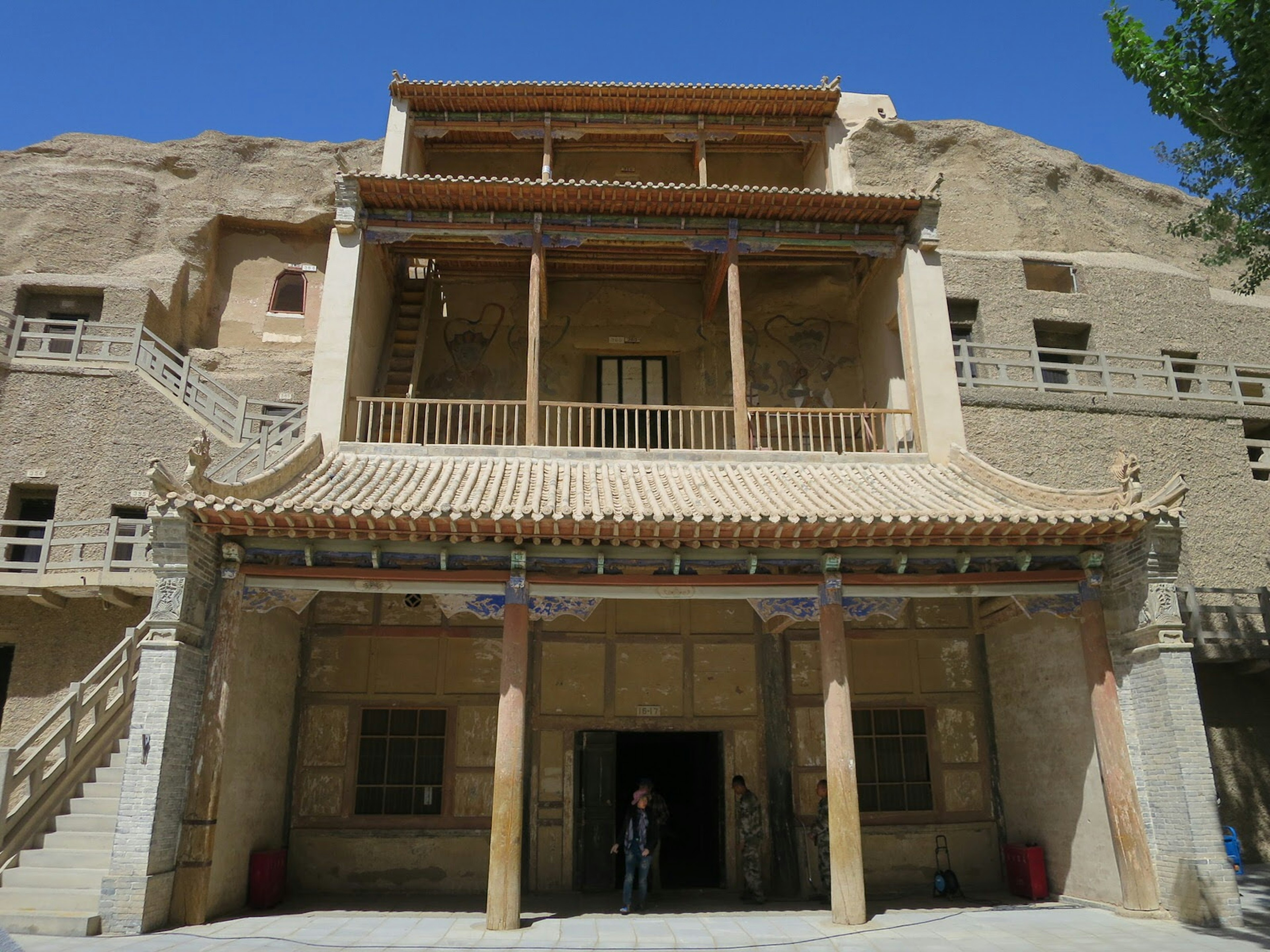 Tiered entrance to one of the grottoes, with upturned Chinese-style eaves, tiled porticos and wooden beams set into a desert cliff.