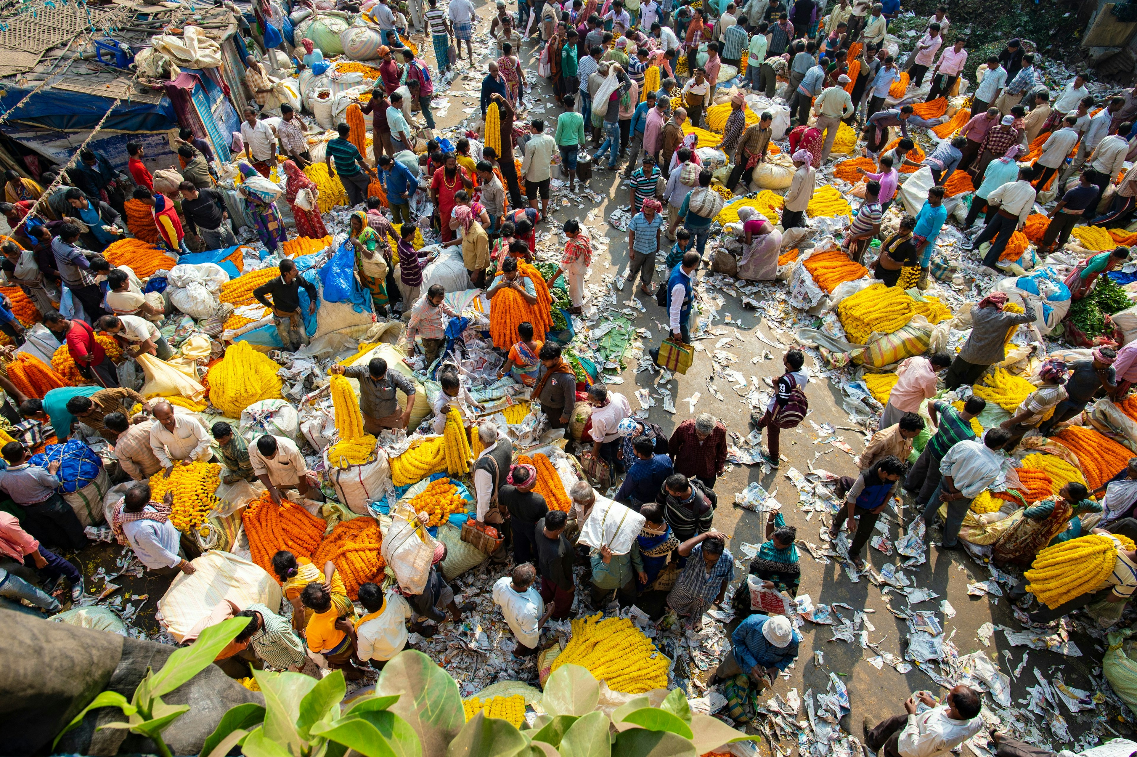 Mullik Ghat Flower Market as seen from above. Bags of different colourful flowers are strewn across the streets while crowds of customers peruse the goods.