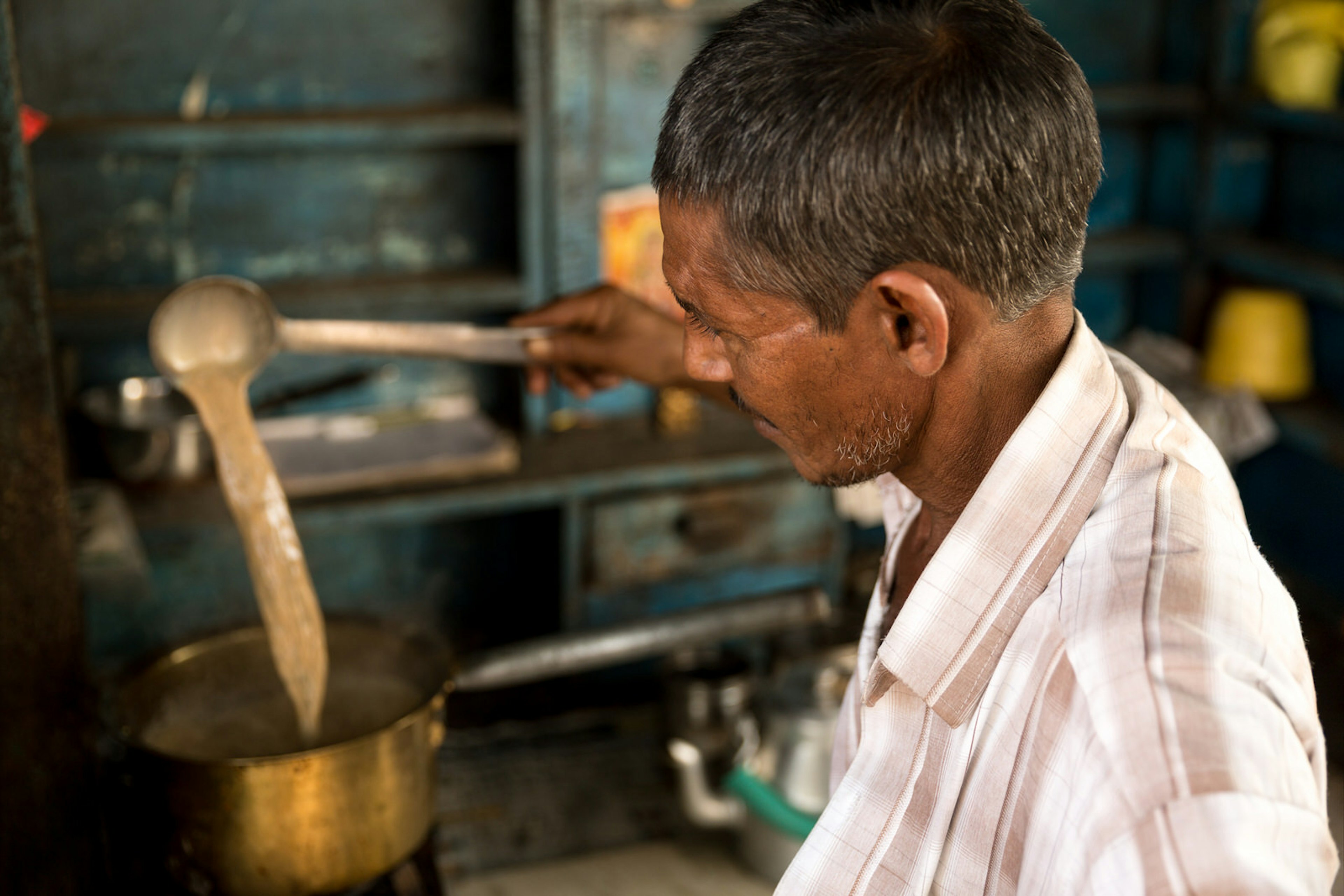 A chai wallah preparing chai in a pan