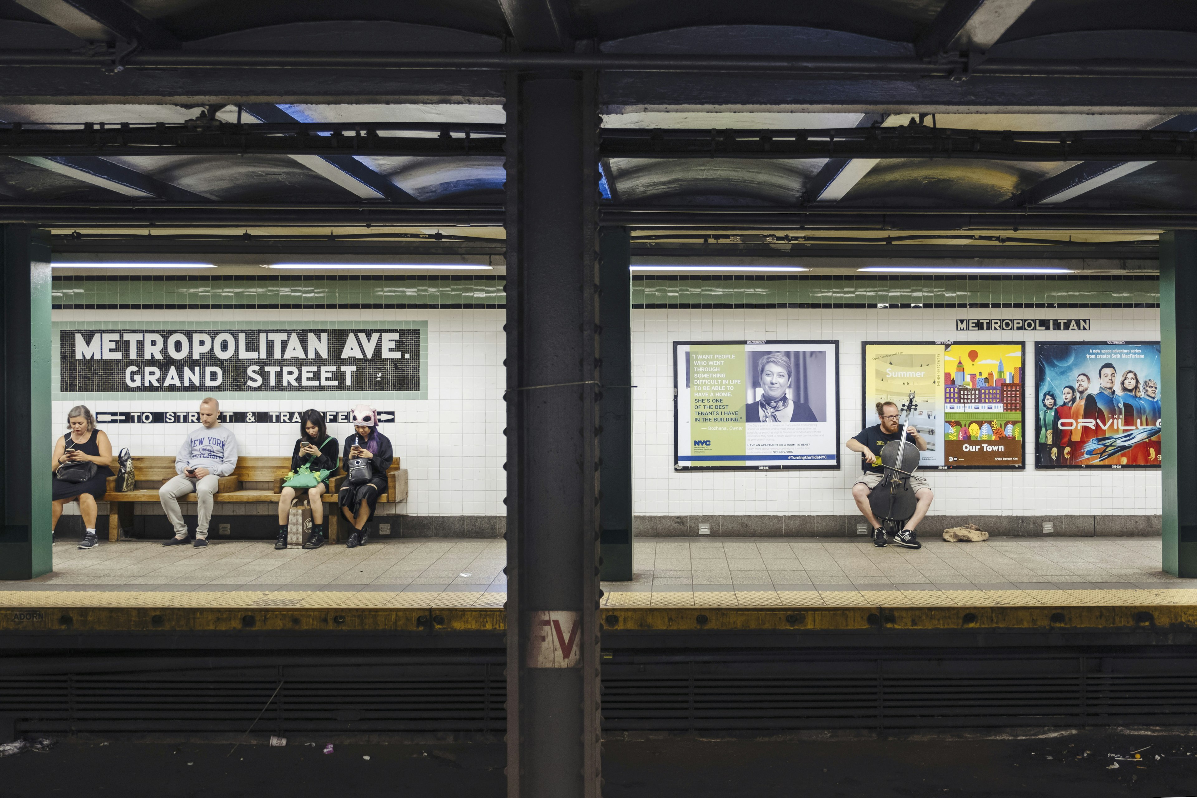 People sit on benches inside a New York subway station.