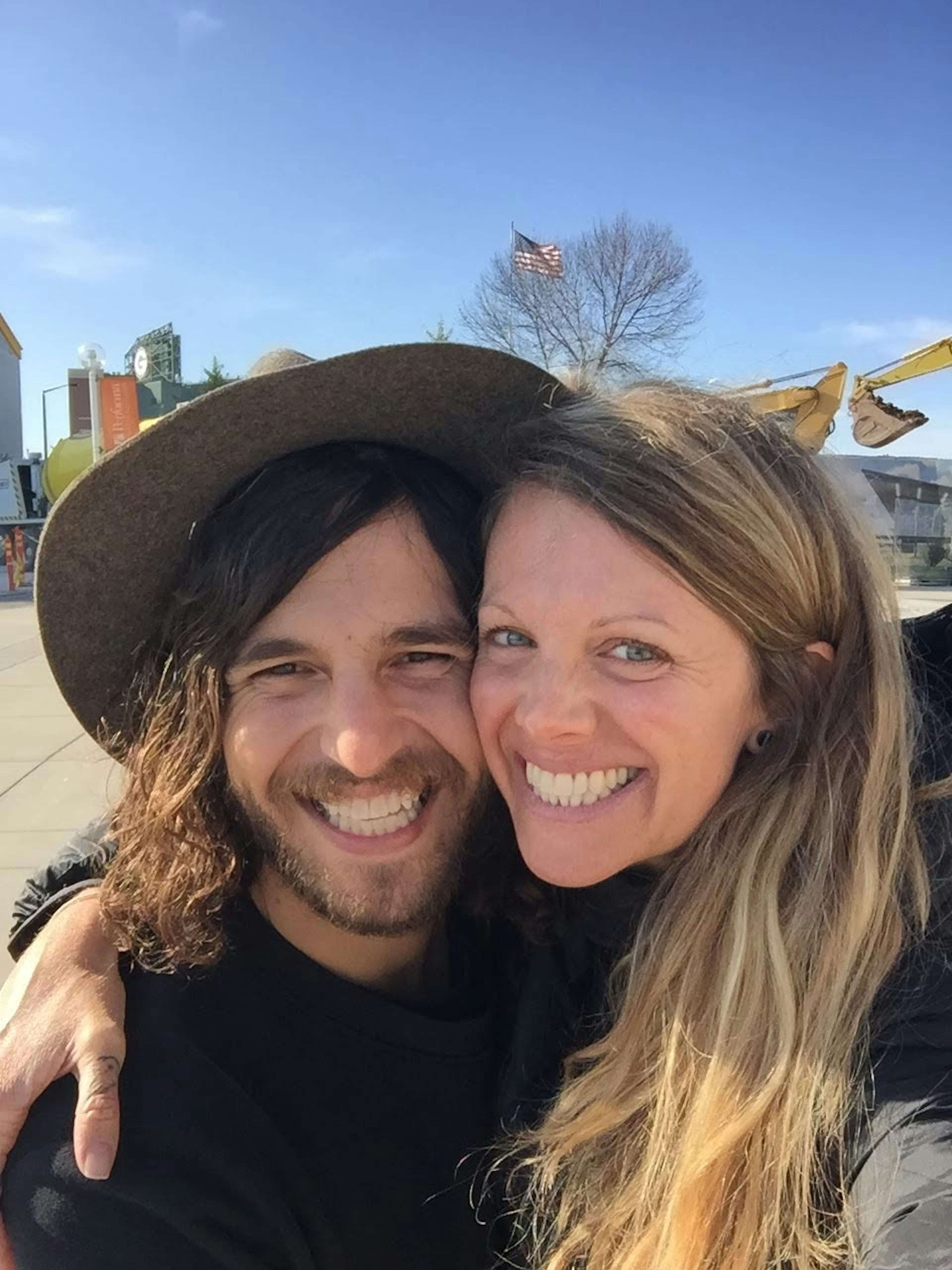 Nik and Lindsey hug for the camera in front of a sports stadium in Wisconsin