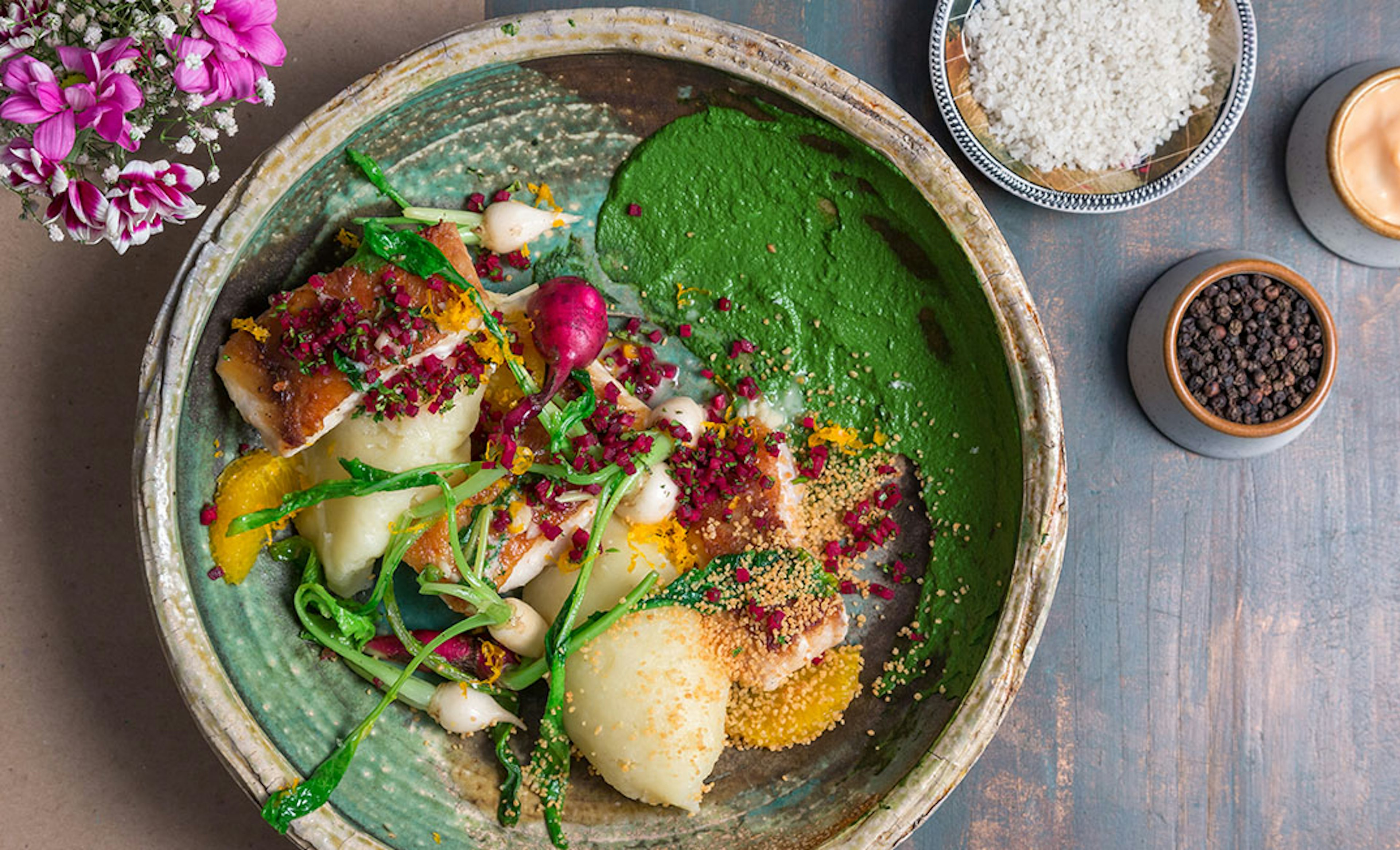 A top-down view of a dish served at the Olive Bar & Kitchen in Mumbai. The dish consists of potatoes, meat and root vegetables, accompanied by a green sauce, and displayed meticulously on the plate.