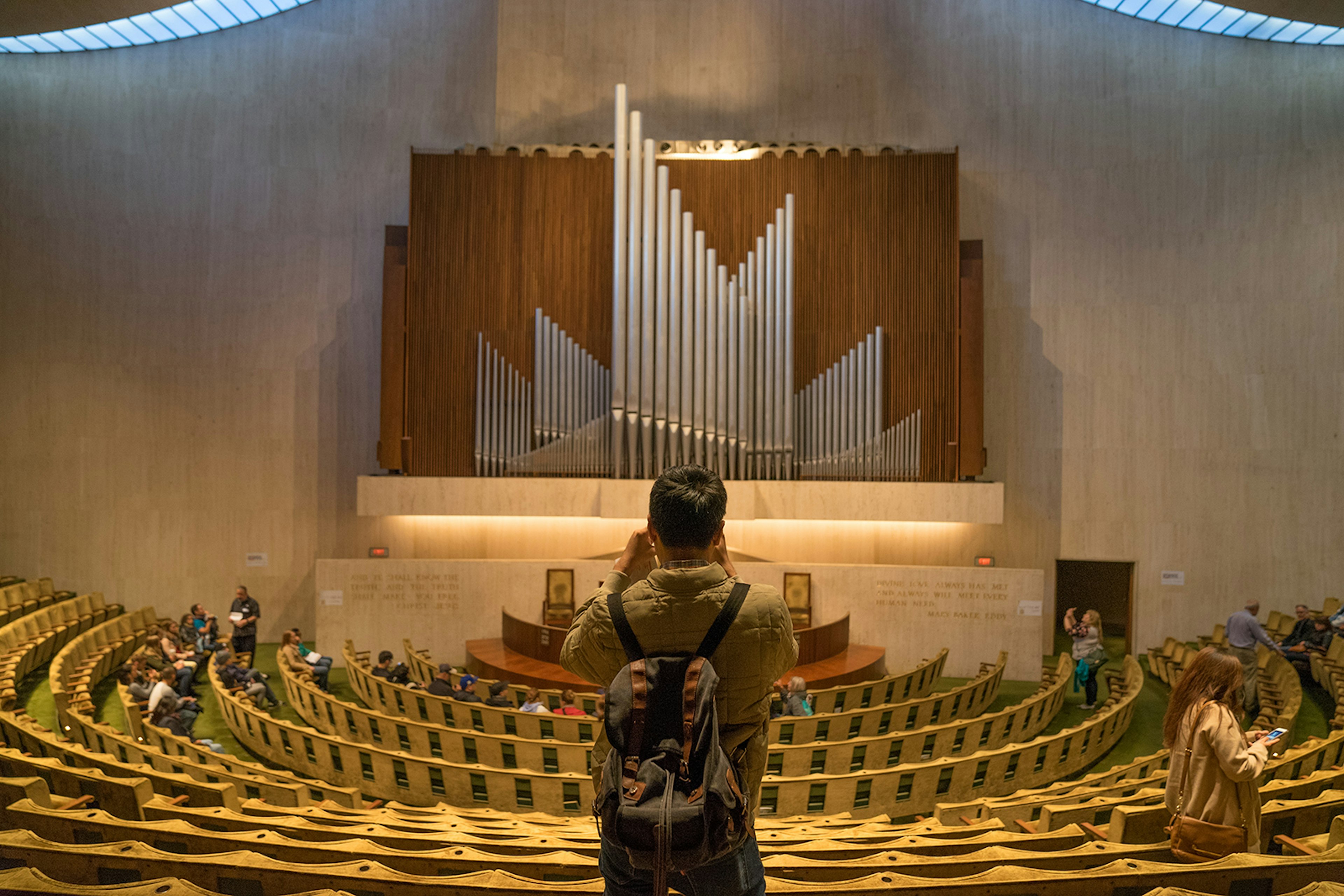 a man with a backpack photographs the modernist organ in the Seventeenth Church of Christ, Scientist