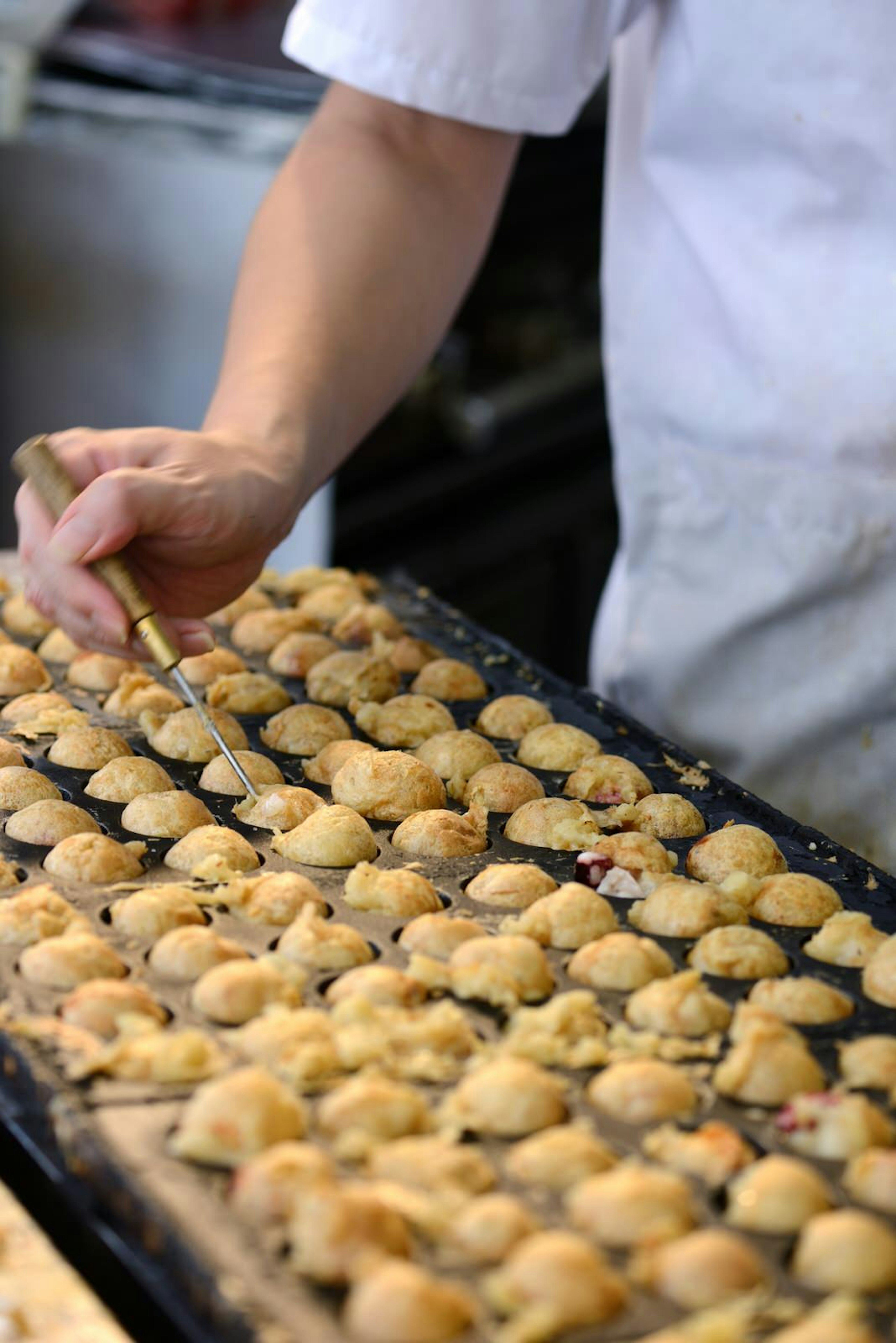 Tako-yaki (octopus balls) are speared and flipped during cooking