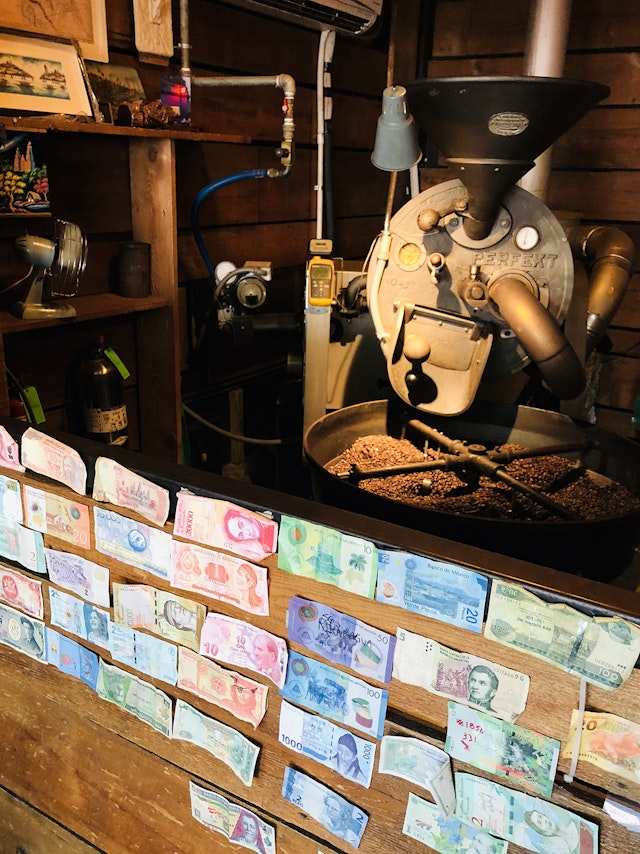 A Perfekt coffee roaster sits behind a wall of colorful currency in Panther Coffee in Florida.