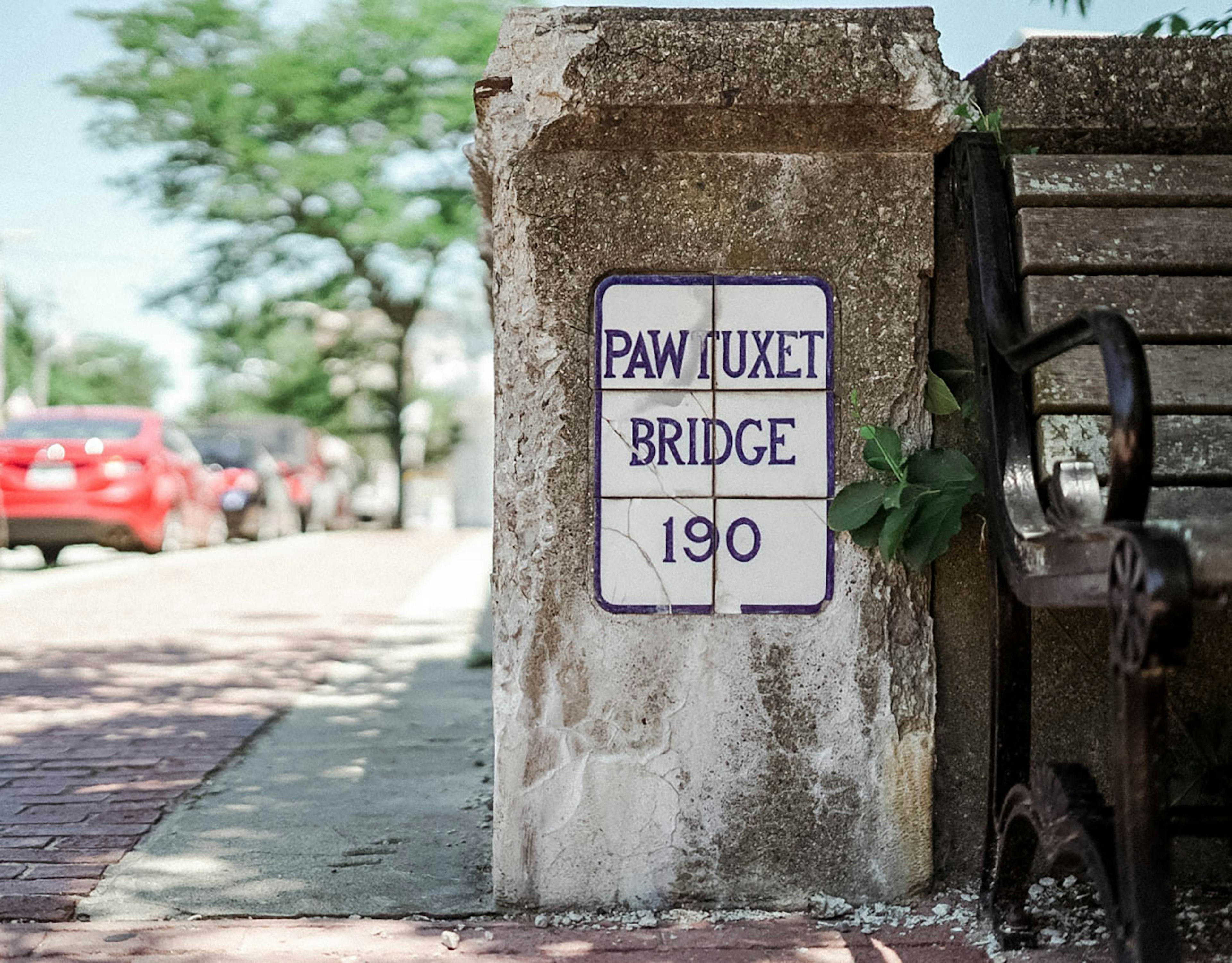 Close-up shot of a vintage Pawtuxet Bridge sign next to a bench in Rhode Island © Anna Saxon / Lonely Planet