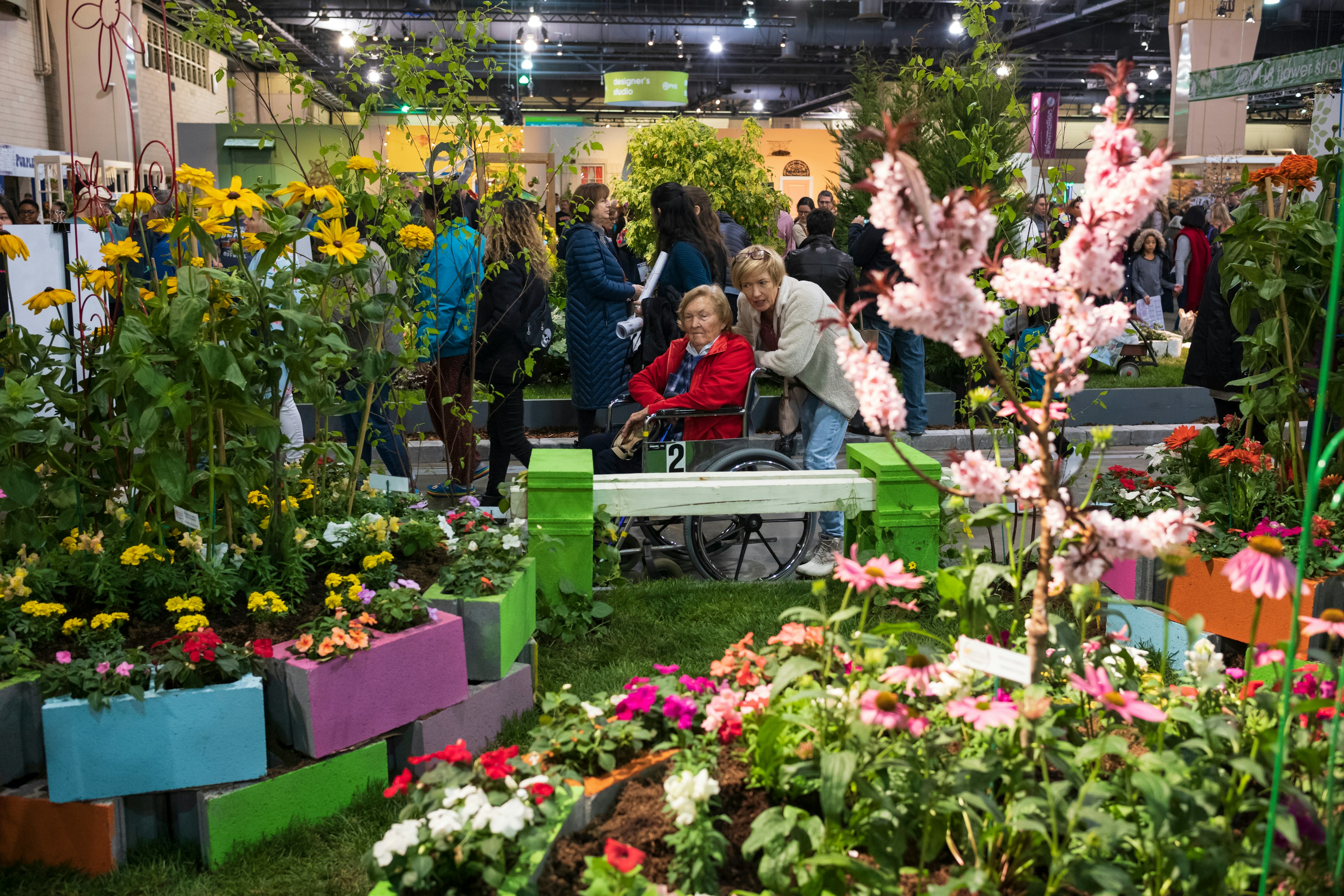 A small crowd of people looking at indoor display gardens at the Pennsylvania Flower Show.