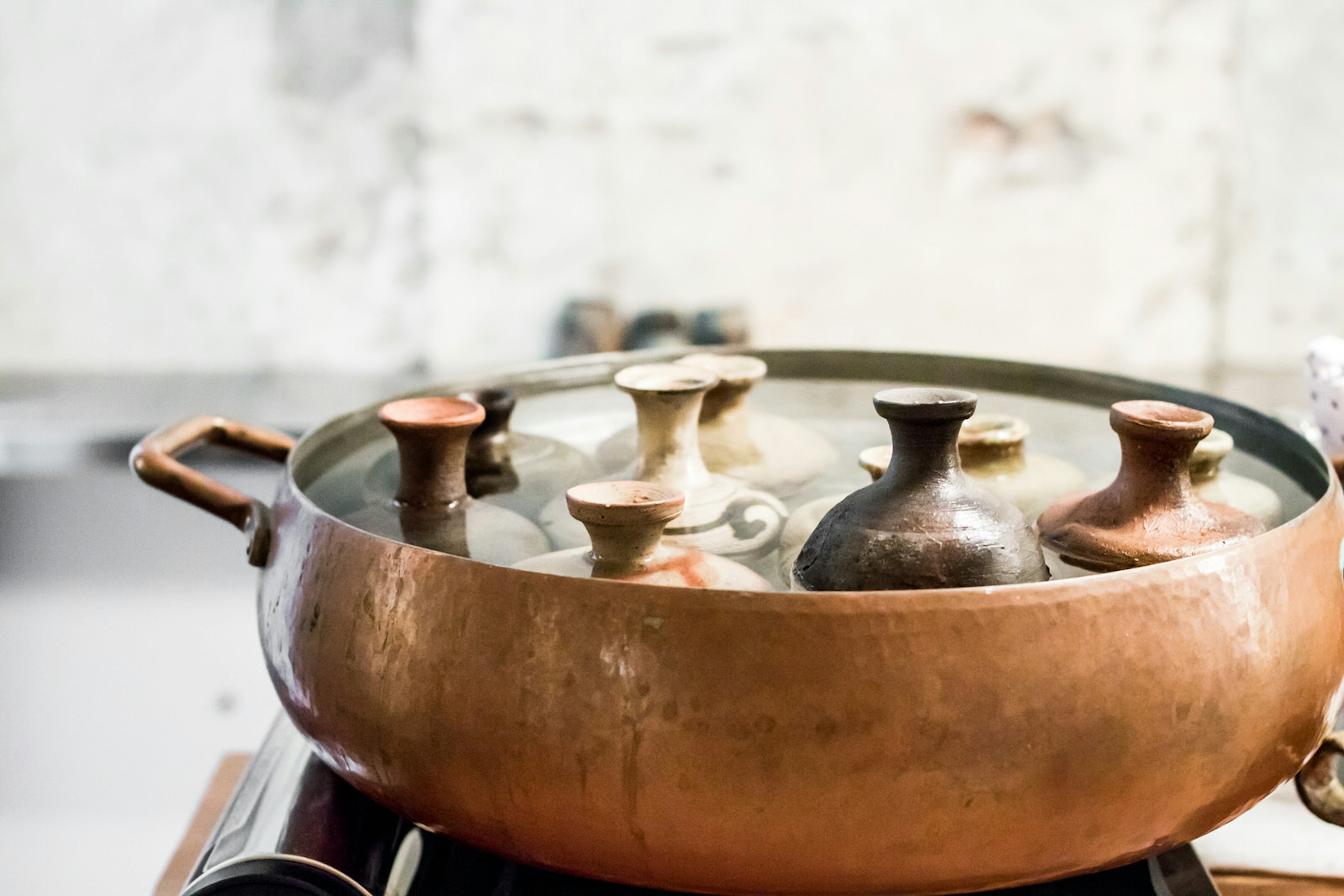 Sake bottles are warmed in a large copper dish filled with water © Melissa Tse / Getty Images