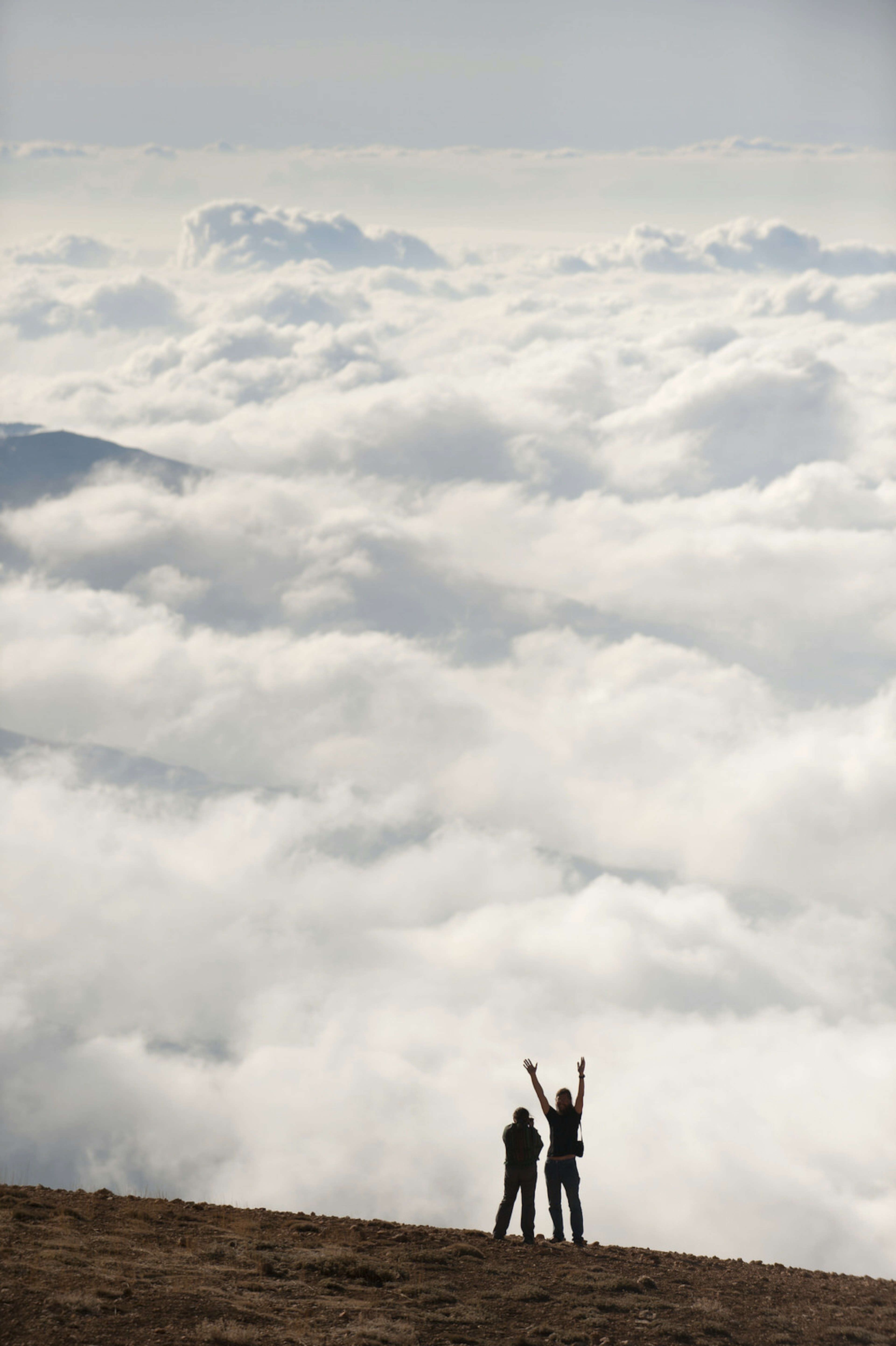 Couple taking pictures above cloud base and Qadisha Valley from Mt Lebanon Range mid-afternoon. Image by Keven Osborne / Fox Fotos / Getty Images