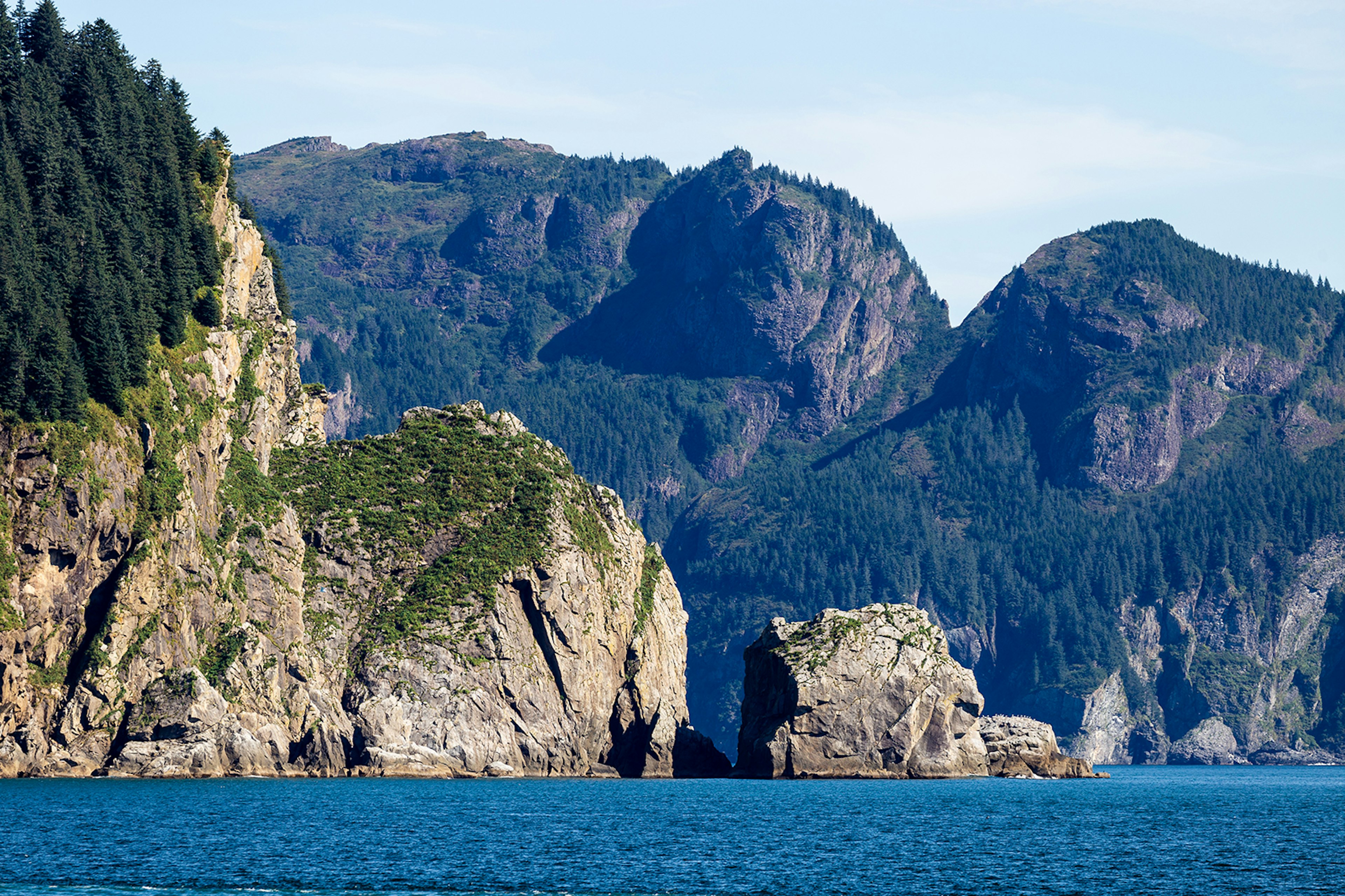 A rocky shoreline with mountains in the distance