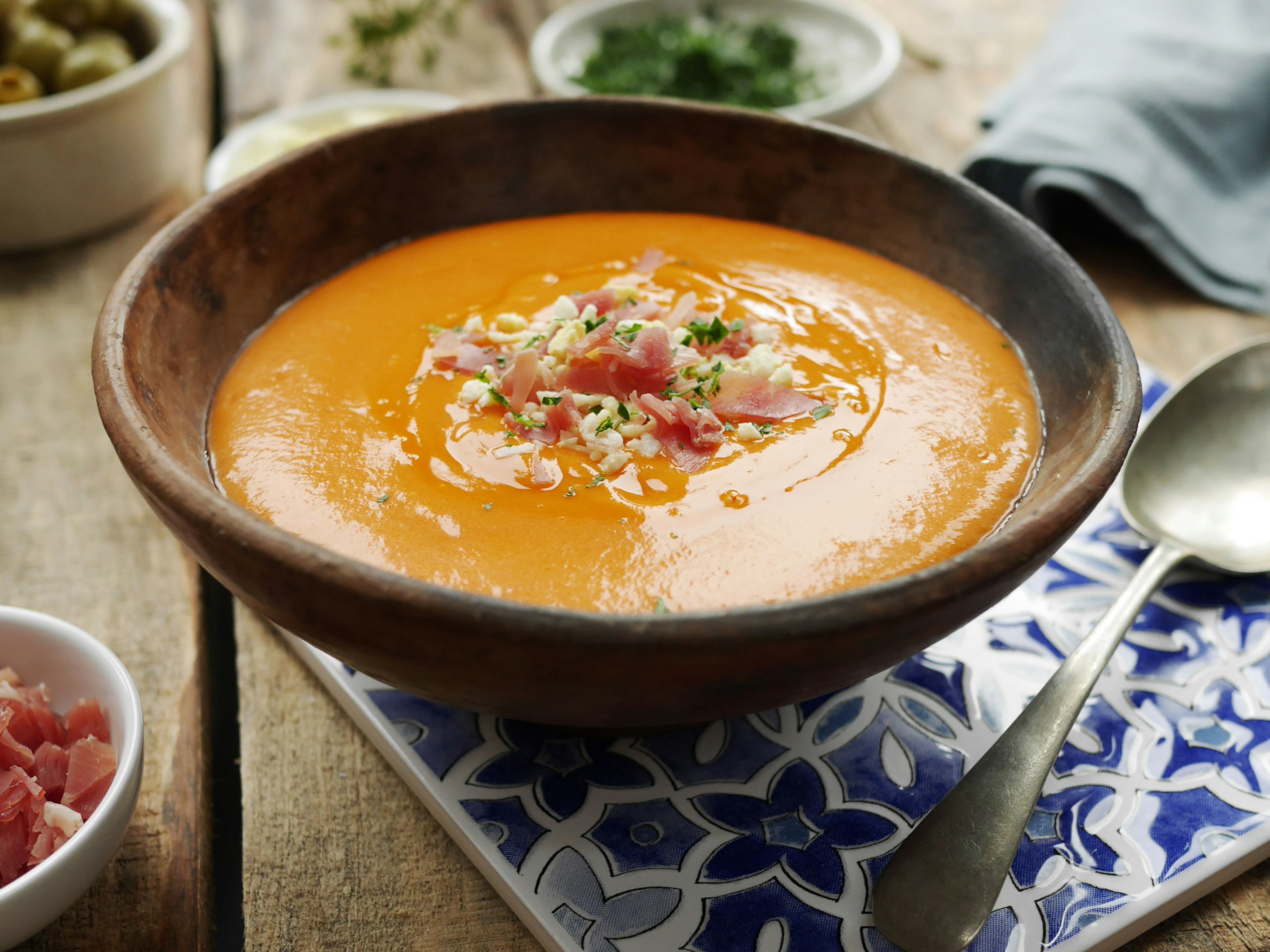 A bowl of salmorejo on a blue, tiled placemat