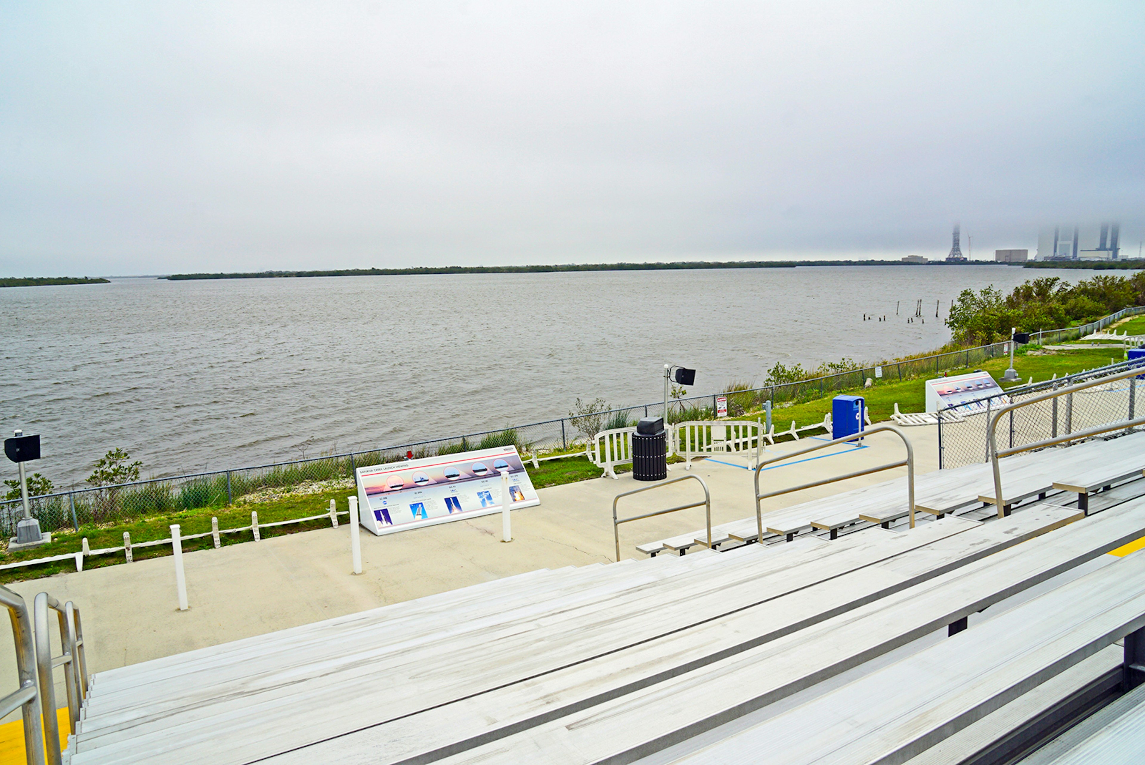 bleachers facing the ocean on the Florida coast, with a shuttle launchpad in the distance; how to experience a rocket launch in Florida