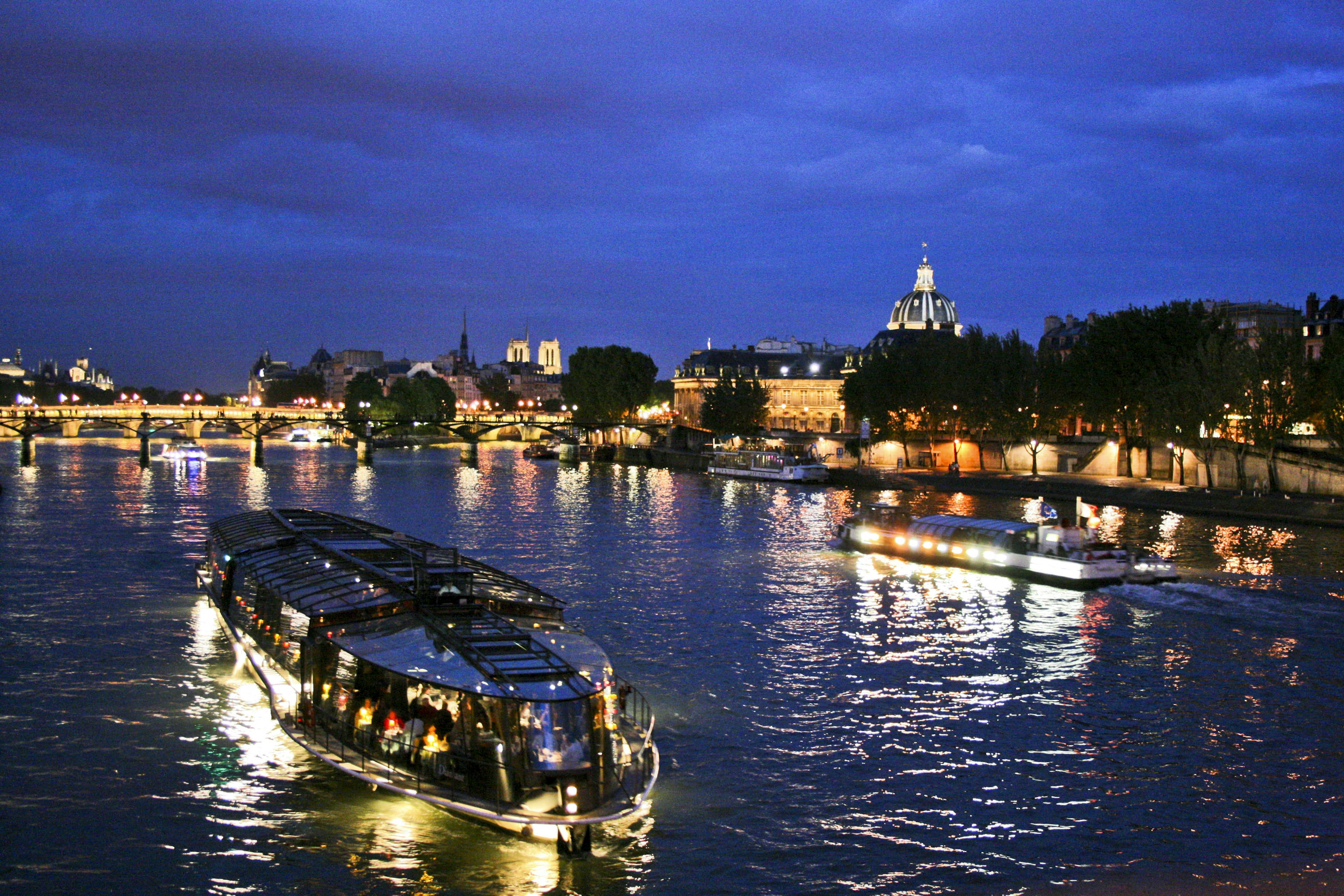 A boat makes its way along a wide river at night